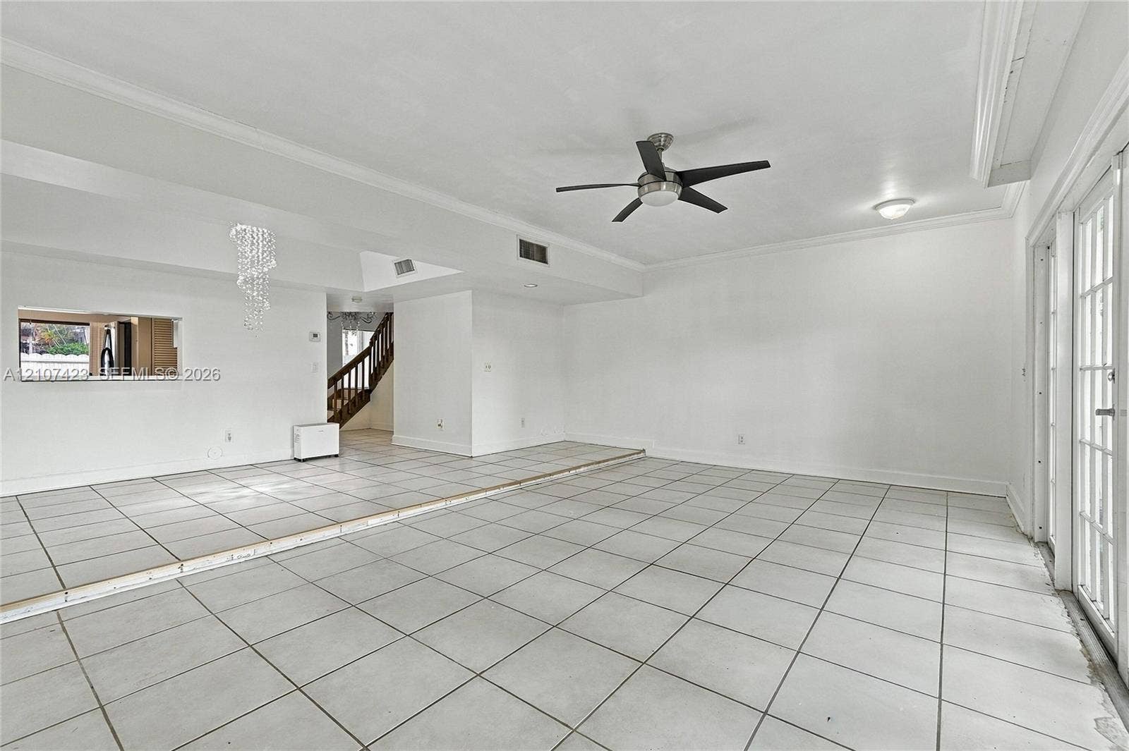 650 NE 195th Street, Miami, FL 33179 Sunken living area featuring large-format tile flooring, a tiered floor plan, a ceiling fan, and multi-pane glass doors