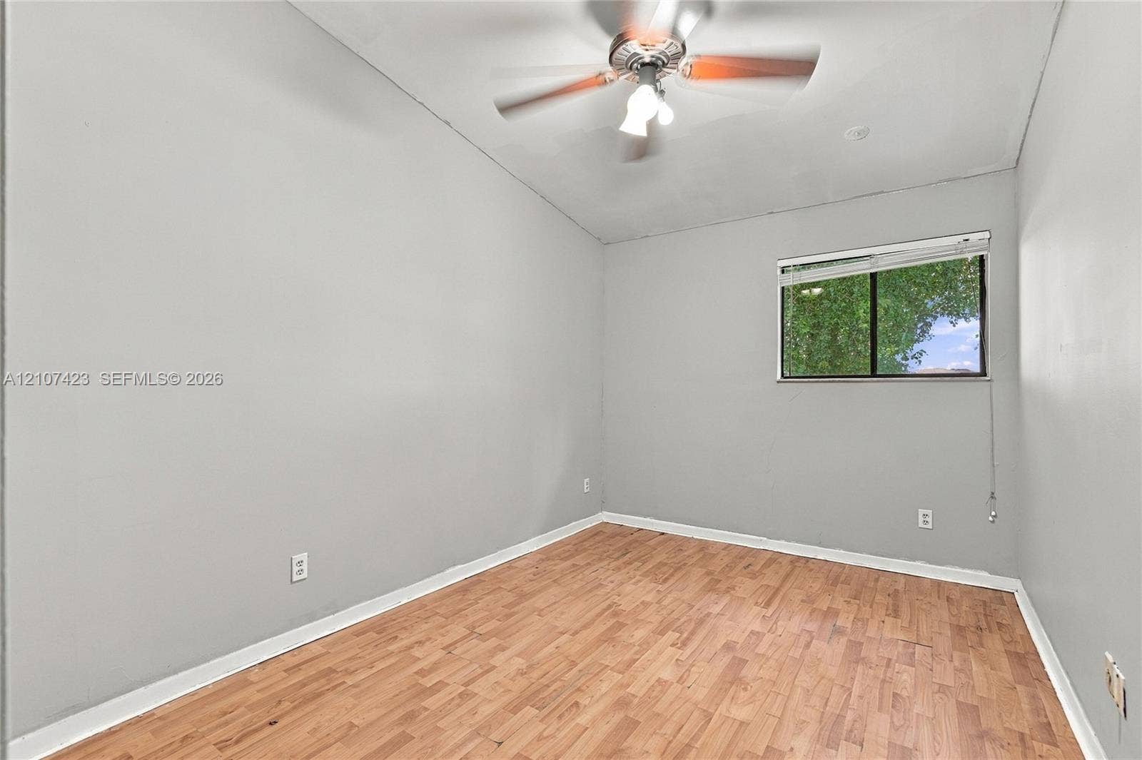 650 NE 195th Street, Miami, FL 33179 Interior room featuring wood-finish flooring, neutral wall tones, a ceiling fan with integrated lighting, and a single-pane window