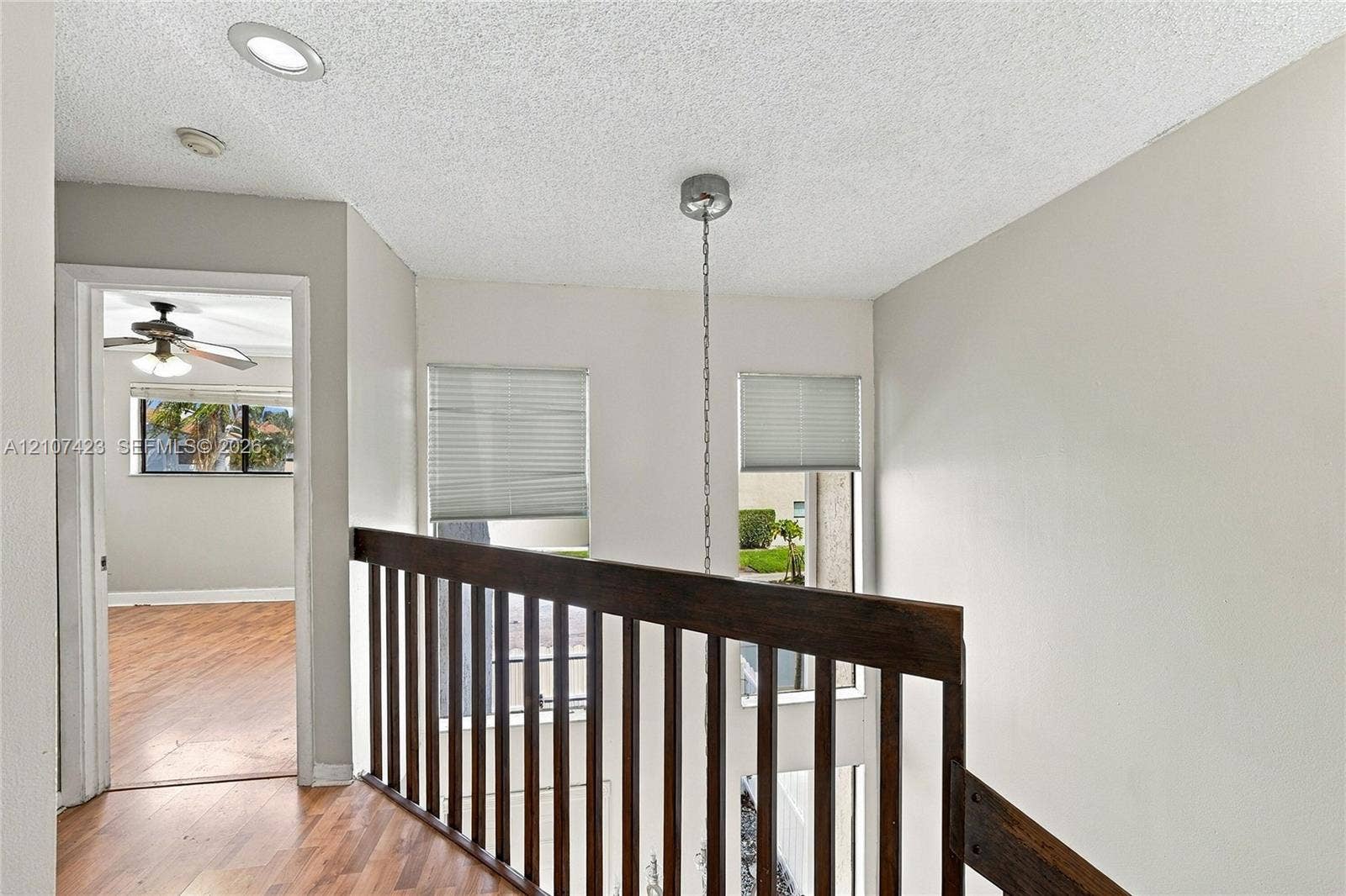 650 NE 195th Street, Miami, FL 33179 Landing area featuring wood-finish flooring, recessed lighting, a stained wood railing, and dual vertical windows