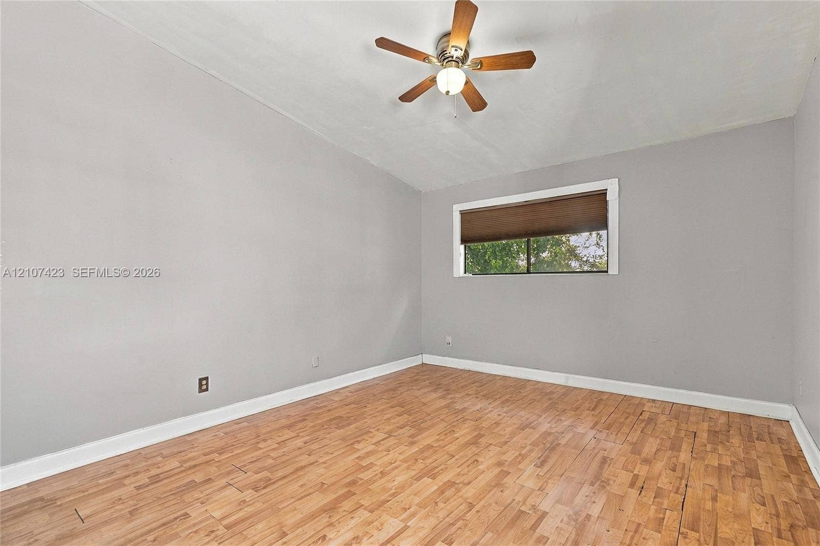 650 NE 195th Street, Miami, FL 33179 Room featuring wood-finish flooring, neutral wall paint, and a ceiling-mounted fan with integrated light fixture