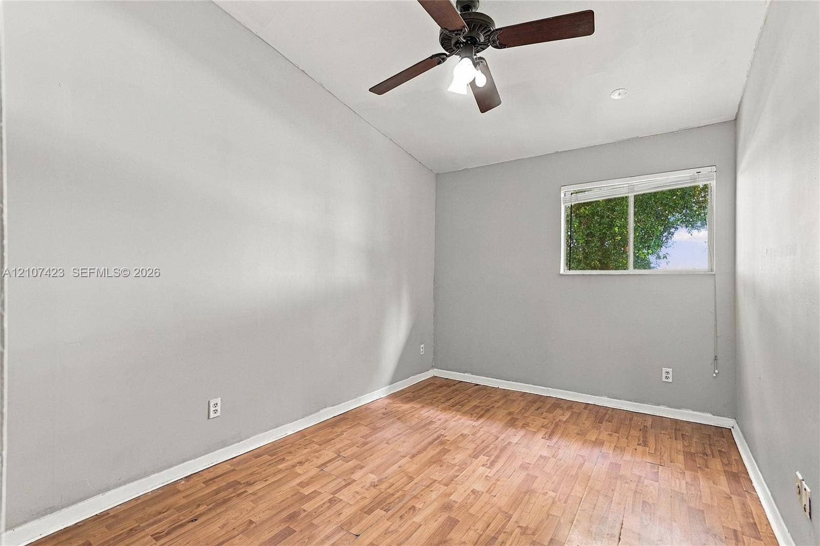 650 NE 195th Street, Miami, FL 33179 Room with wood-finish flooring, neutral wall paint, vaulted ceiling, multi-blade ceiling fan with integrated lighting, and horizontal sliding window