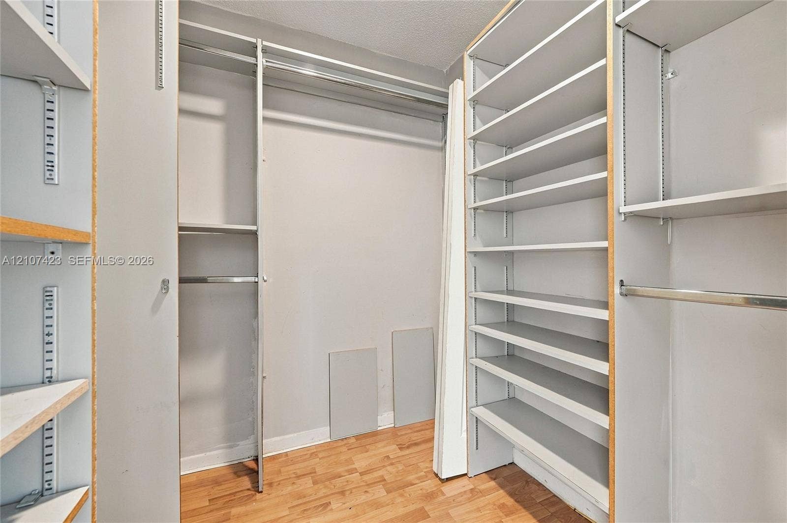 650 NE 195th Street, Miami, FL 33179 Storage area featuring adjustable shelving units, metal hanging rods, and wood-finish flooring