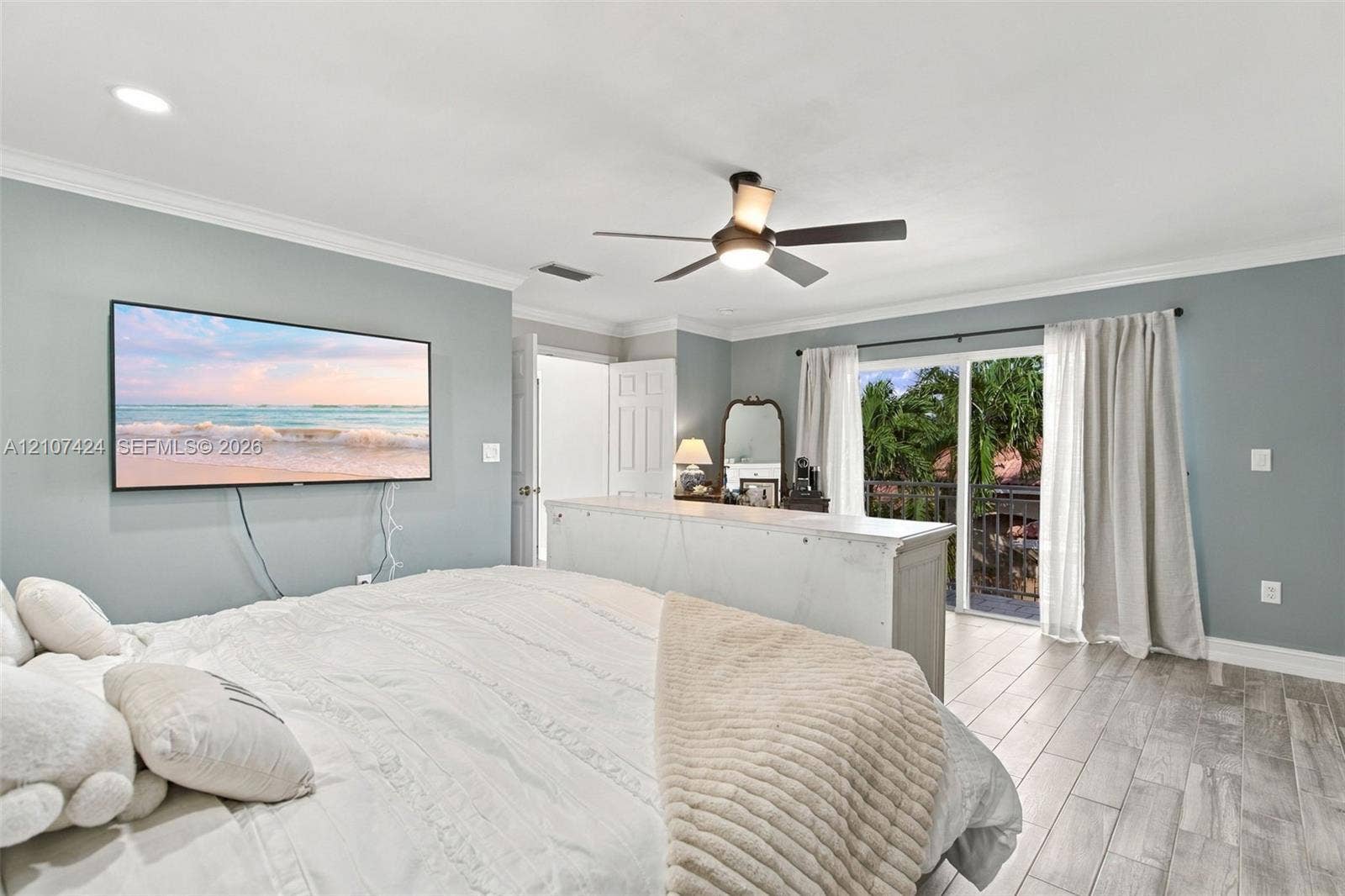 14702 Vista Luna Drive, Davie, FL 33325 Living space featuring wood-finish tile flooring, crown molding, a central ceiling fan with integrated lighting, and a sliding glass door providing external access