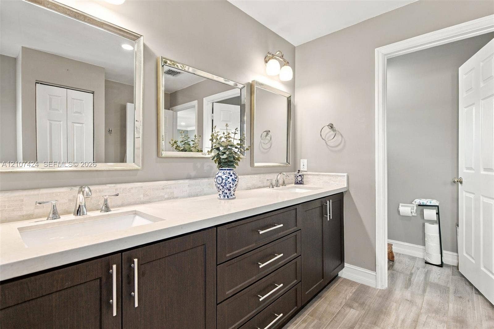 14702 Vista Luna Drive, Davie, FL 33325 Double vanity featuring dark espresso cabinetry, stone-finish countertops, dual rectangular undermount sinks, polished chrome hardware, and three separate rectangular mirrors