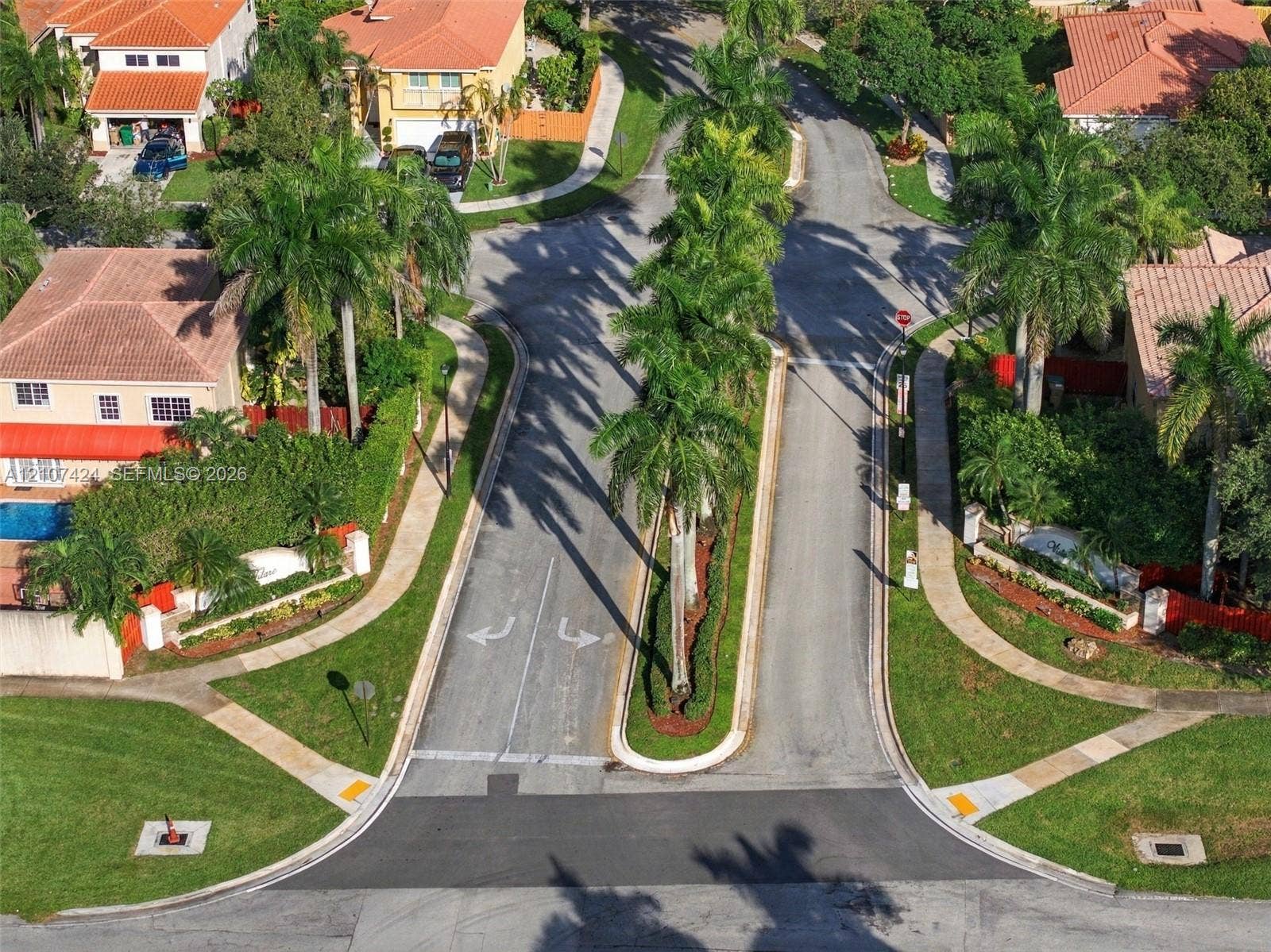 14702 Vista Luna Drive, Davie, FL 33325 Aerial perspective of a residential street featuring a palm-lined median, asphalt roadways, sidewalks, and surrounding landscaped grounds