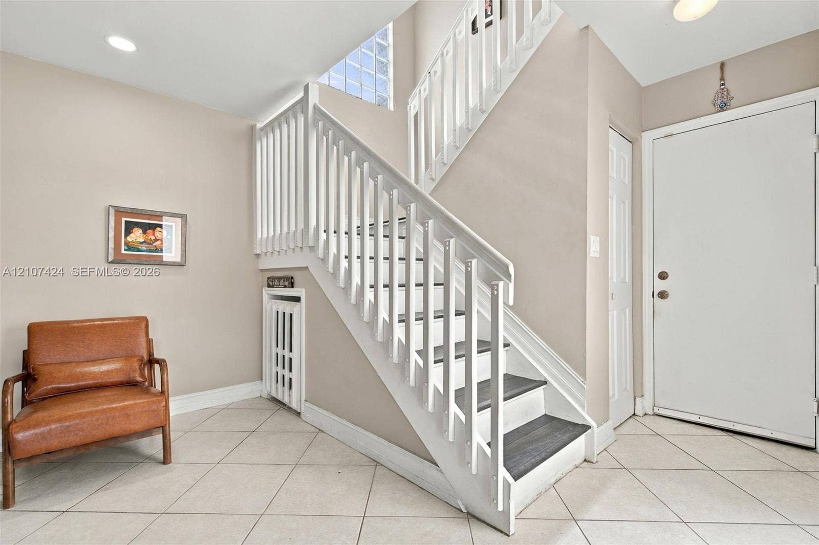 14702 Vista Luna Drive, Davie, FL 33325 Foyer featuring ceramic tile flooring, a white staircase with dark treads and wood-finish railings, and glass block accent windows