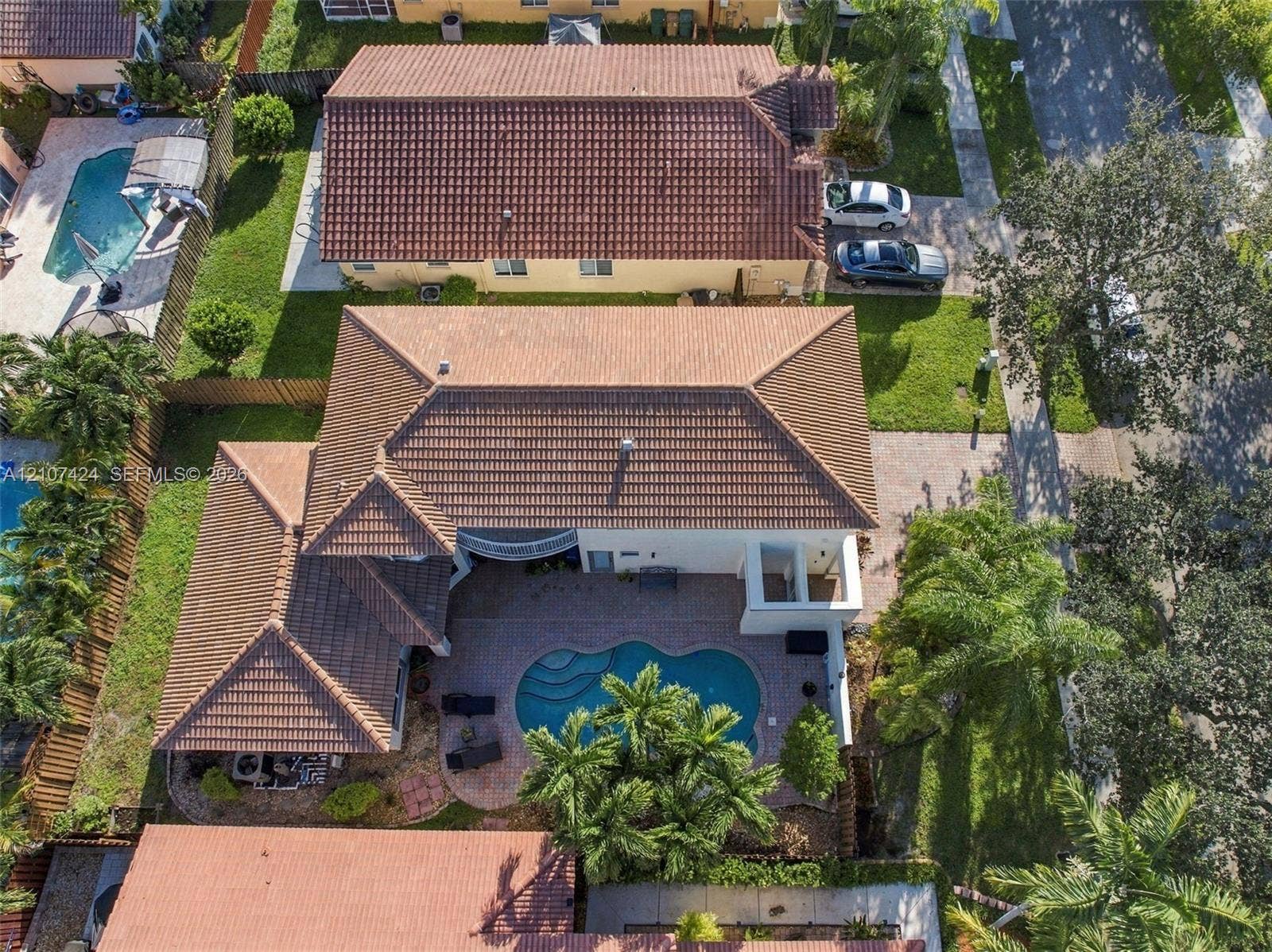 14702 Vista Luna Drive, Davie, FL 33325 Aerial perspective of a multi-gabled residence featuring a concrete tile roof, paver patio, in-ground swimming pool, and landscaped perimeter