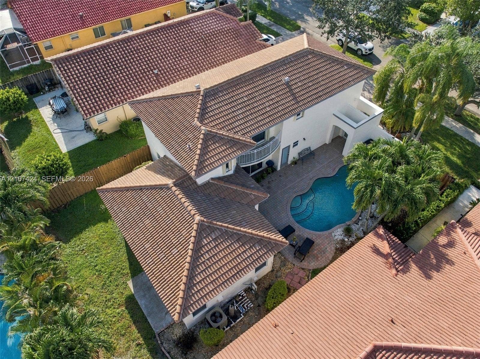 14702 Vista Luna Drive, Davie, FL 33325 Two-story residence featuring a tile roof, an upper-level balcony, a swimming pool with integrated spa, and paver hardscaping
