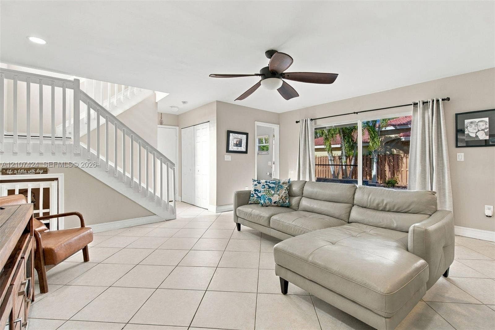 14702 Vista Luna Drive, Davie, FL 33325 Living area featuring large-format ceramic tile flooring, a white wooden staircase with balustrades, a ceiling fan with integrated lighting, and multiple windows
