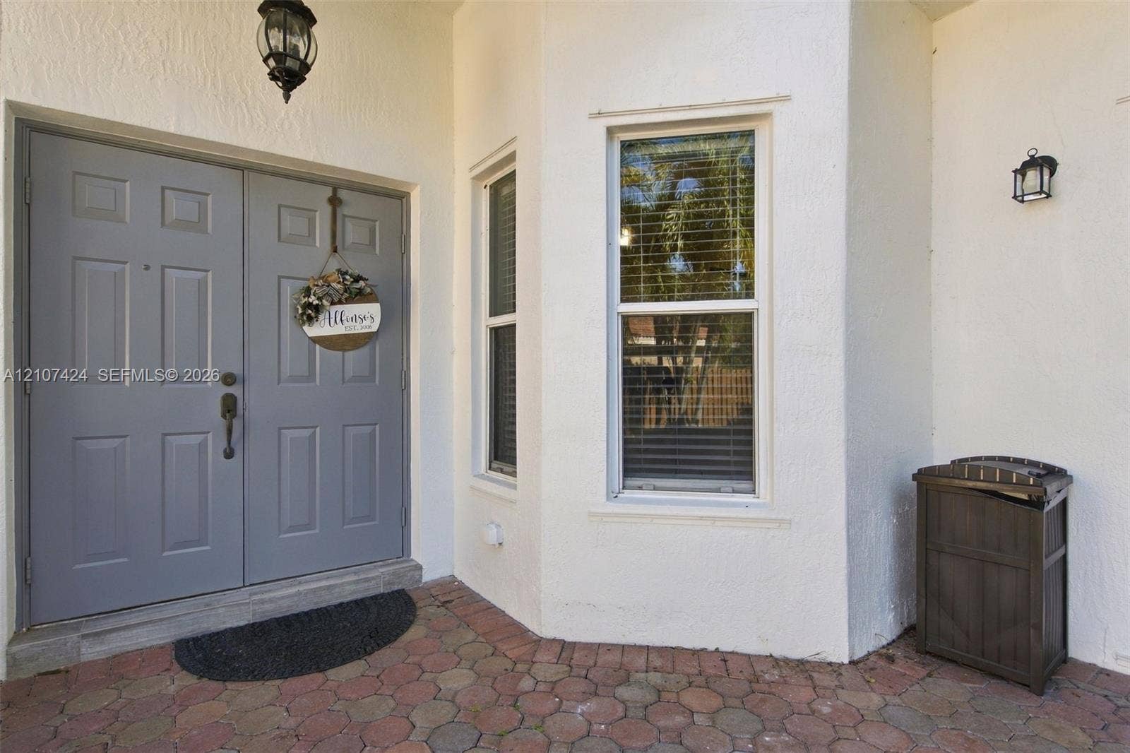 14702 Vista Luna Drive, Davie, FL 33325 Entryway featuring a double-door entrance with paneled detailing, decorative exterior wall-mounted lighting, and a multi-toned paver porch