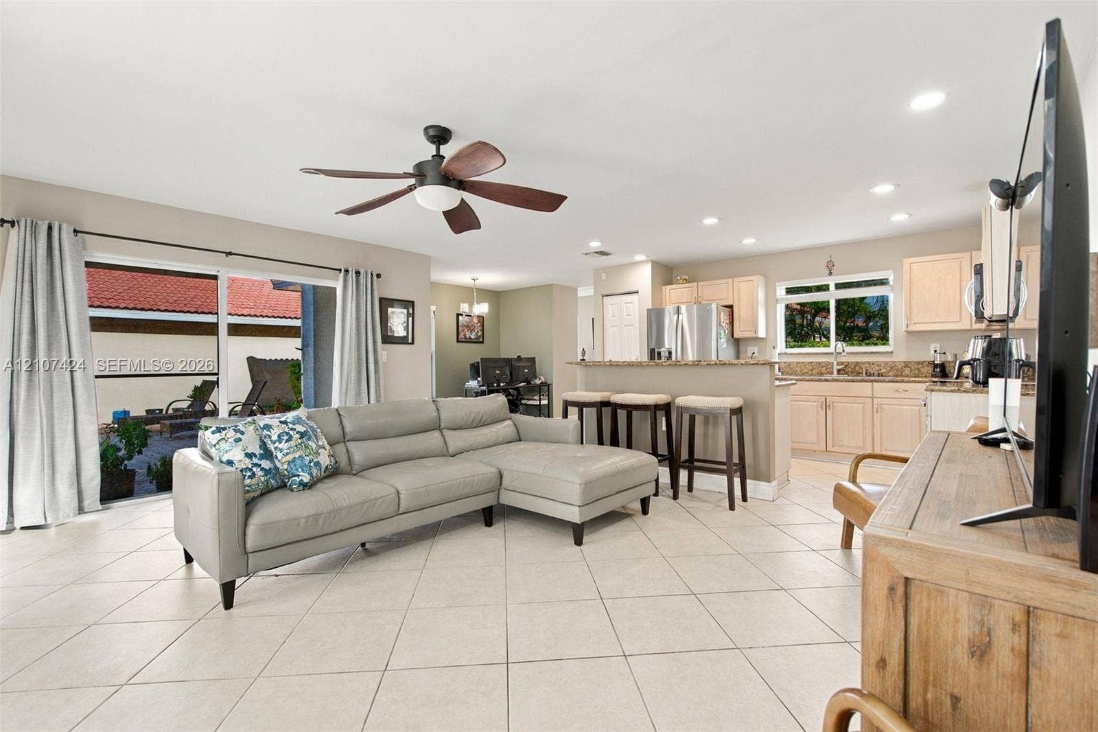 14702 Vista Luna Drive, Davie, FL 33325 Open-concept interior featuring light-toned tile flooring, recessed ceiling lighting, a multi-blade ceiling fan, and sliding glass doors