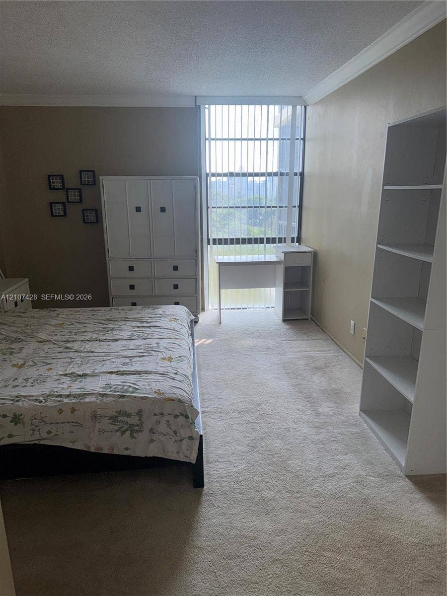 3475 N Country Club Drive, #704, Aventura, Aventura, FL 33180 Floor-to-ceiling windows featuring vertical blinds, neutral carpeting, and crown molding