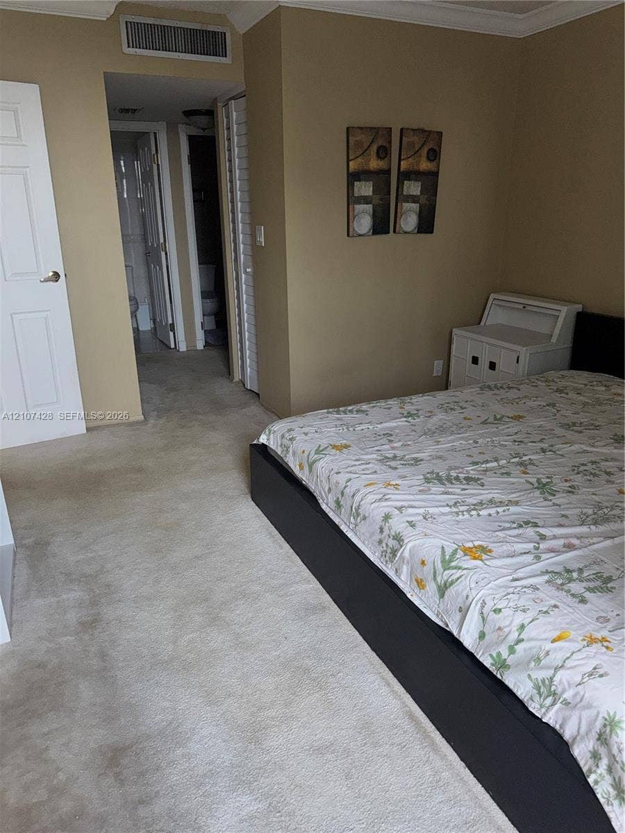 3475 N Country Club Drive, #704, Aventura, Aventura, FL 33180 Room featuring neutral-toned walls, carpeting, crown molding, and louvered closet doors