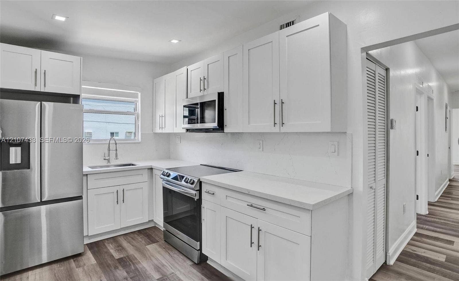 2135 SW 4th Street, Miami, FL 33135 Kitchen featuring white shaker-style cabinetry, quartz countertops, stainless steel appliances, and wood-finish flooring