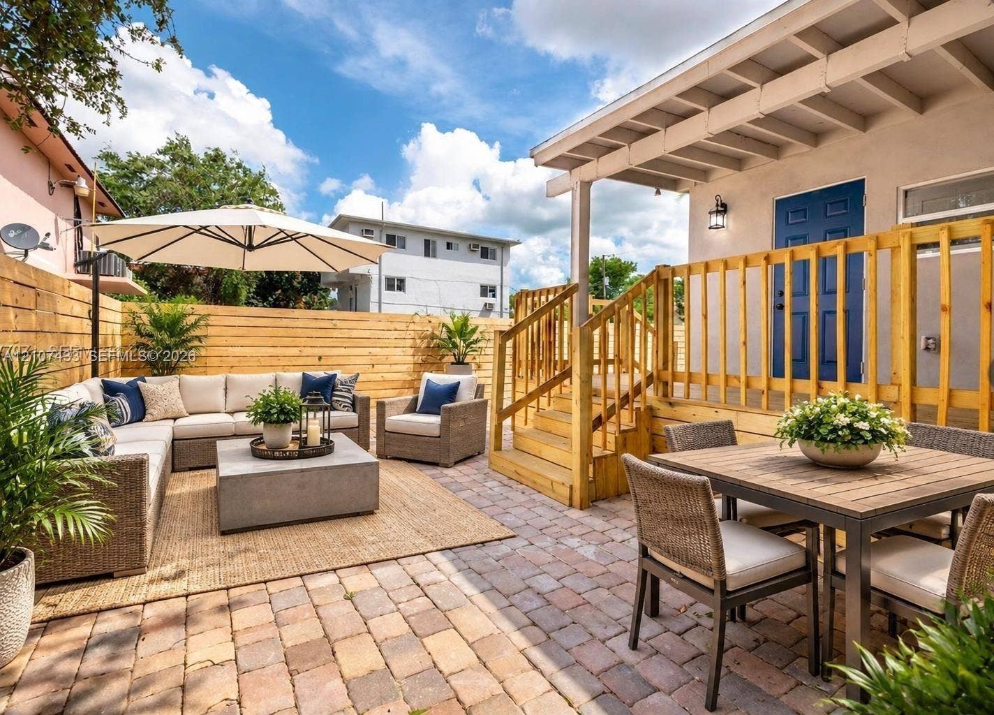2135 SW 4th Street, Miami, FL 33135 Rear patio featuring concrete paver flooring, a raised wooden deck with staircase, and perimeter wood privacy fencing