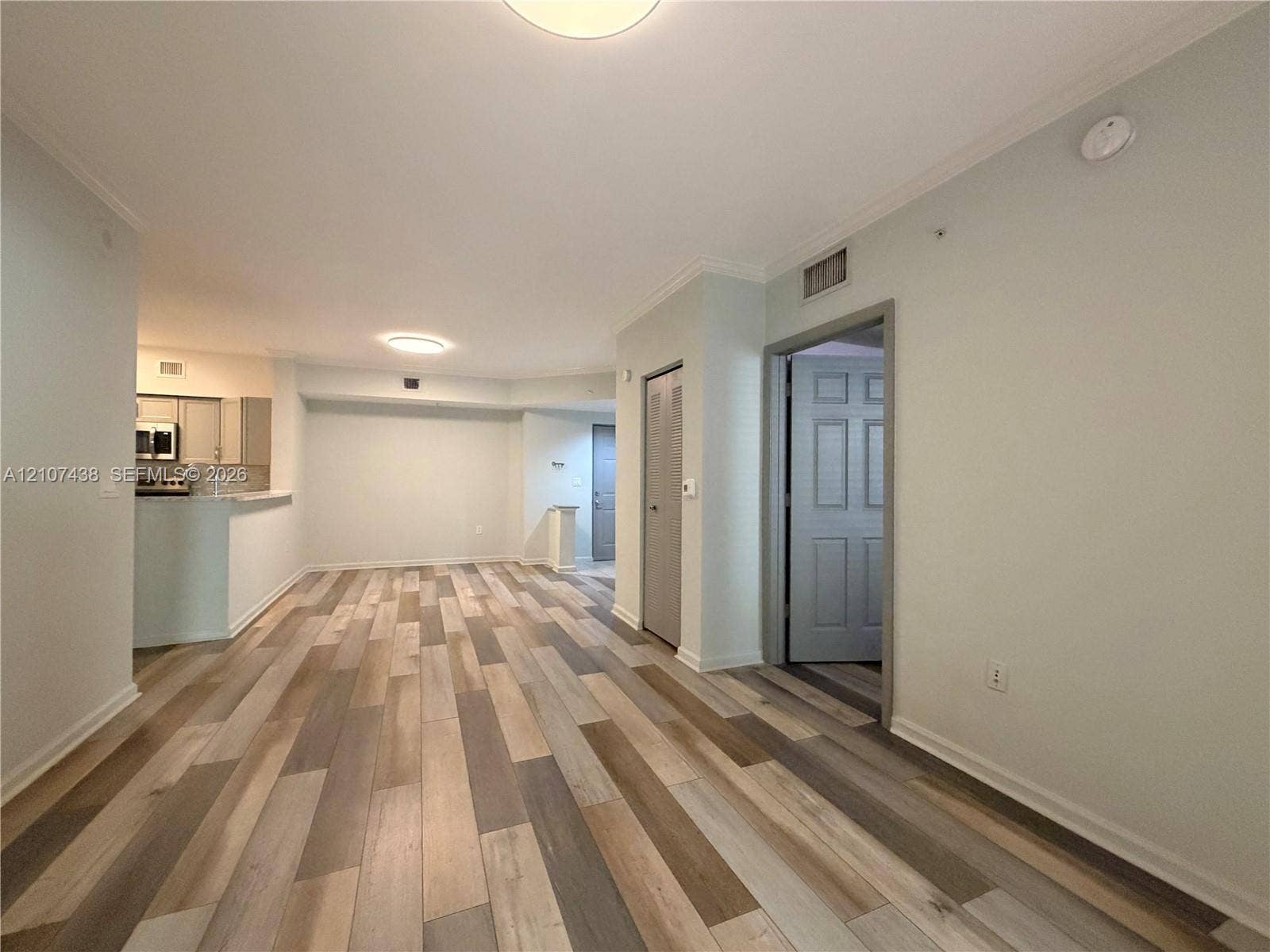 Interior space featuring multi-tonal wood-finish flooring, recessed ceiling lighting, and crown molding