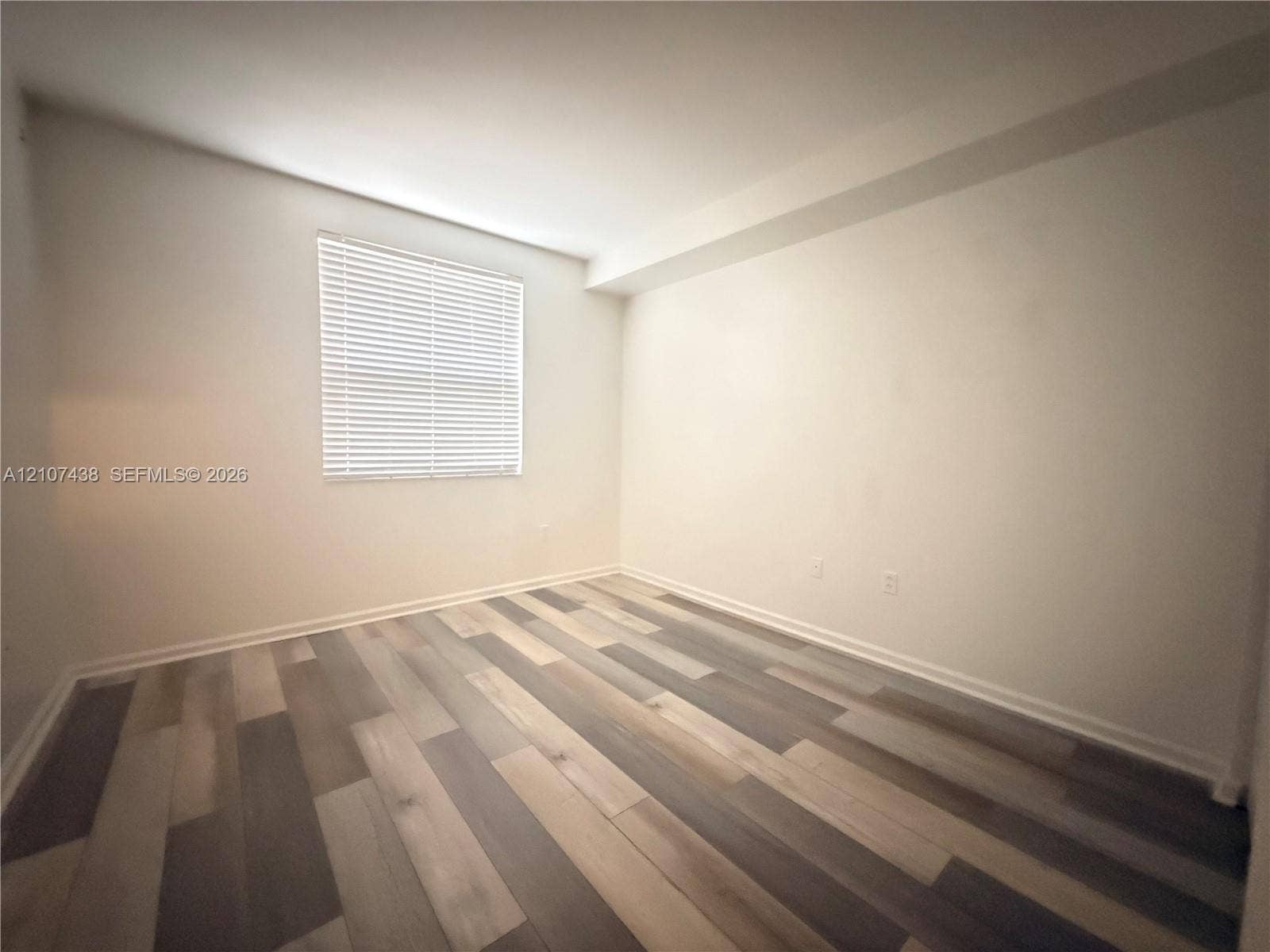 Interior space featuring neutral wall paint and multi-toned wood-finish flooring