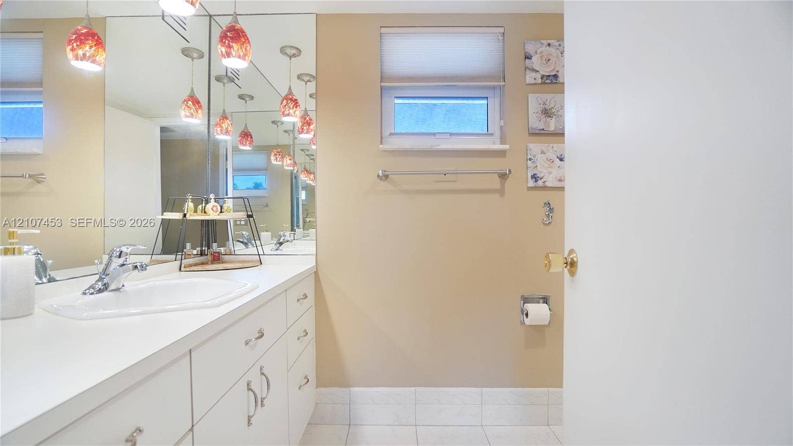 111 N Pompano Beach Boulevard, #304, Pompano Beach, FL 33062 Bathroom featuring a white vanity with a composite countertop and integrated sink, large wall-mounted mirror, multiple pendant light fixtures, and ceramic tile flooring