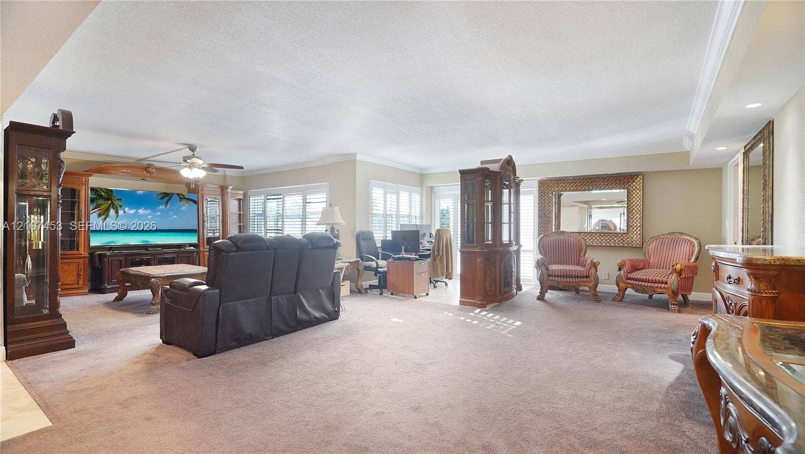 111 N Pompano Beach Boulevard, #304, Pompano Beach, FL 33062 Expansive living area featuring custom built-in wood cabinetry, integrated ceiling fan, and multi-pane windows with shutters