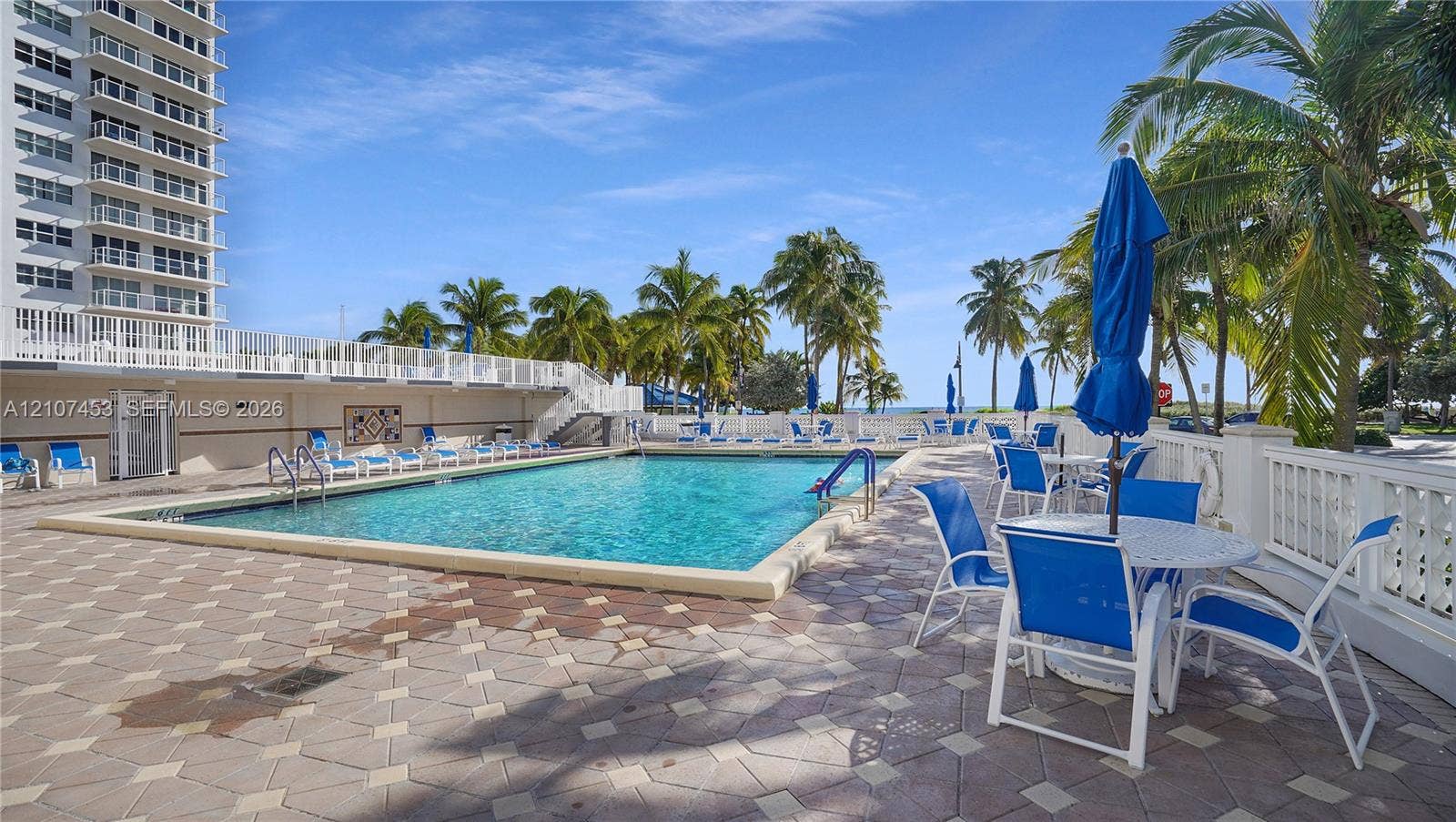111 N Pompano Beach Boulevard, #304, Pompano Beach, FL 33062 Swimming pool with a paved deck, white balustrade fencing, and mature palm trees