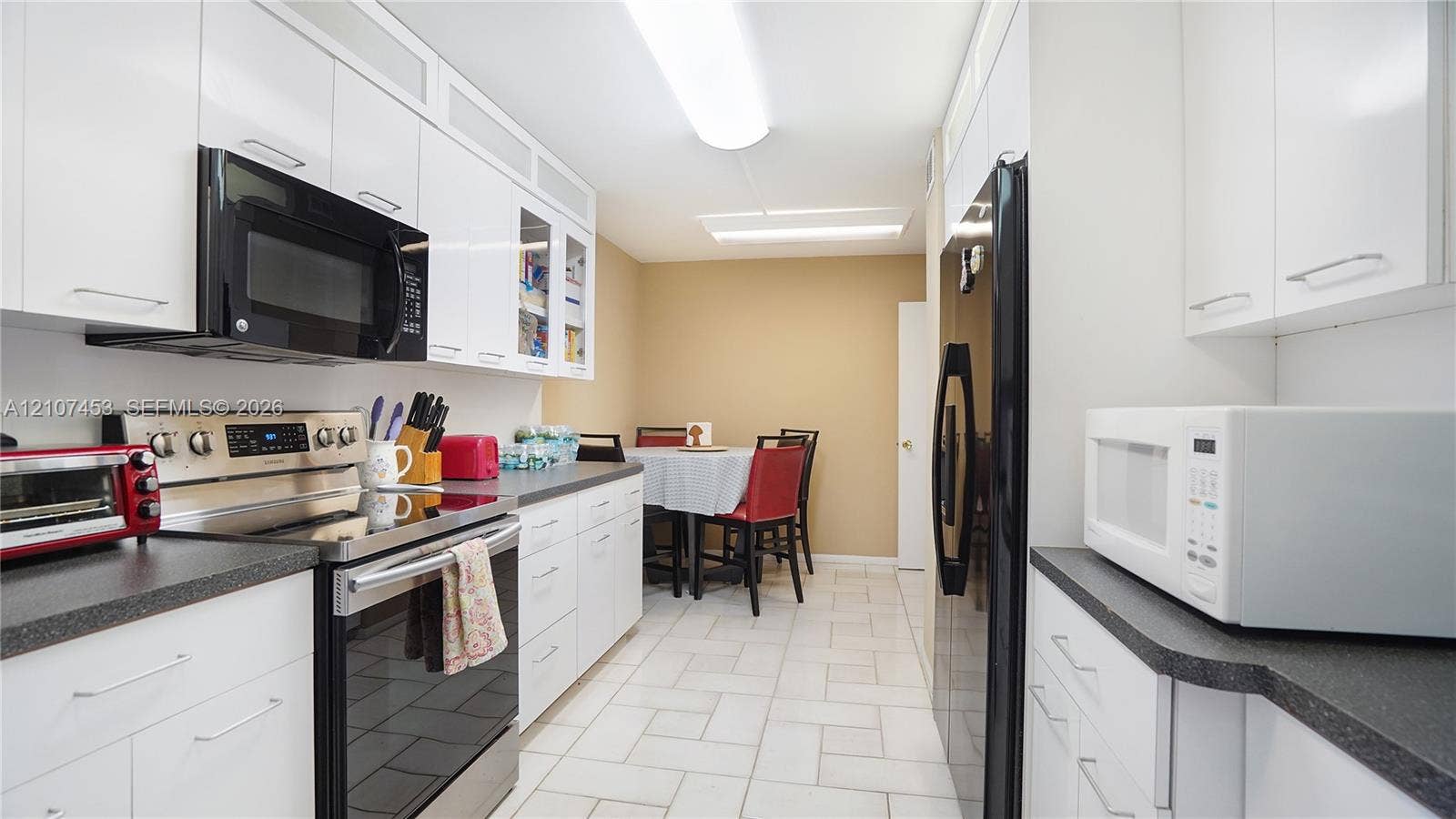 111 N Pompano Beach Boulevard, #304, Pompano Beach, FL 33062 Kitchen featuring white cabinetry, solid-surface countertops, tile flooring, and stainless steel appliances