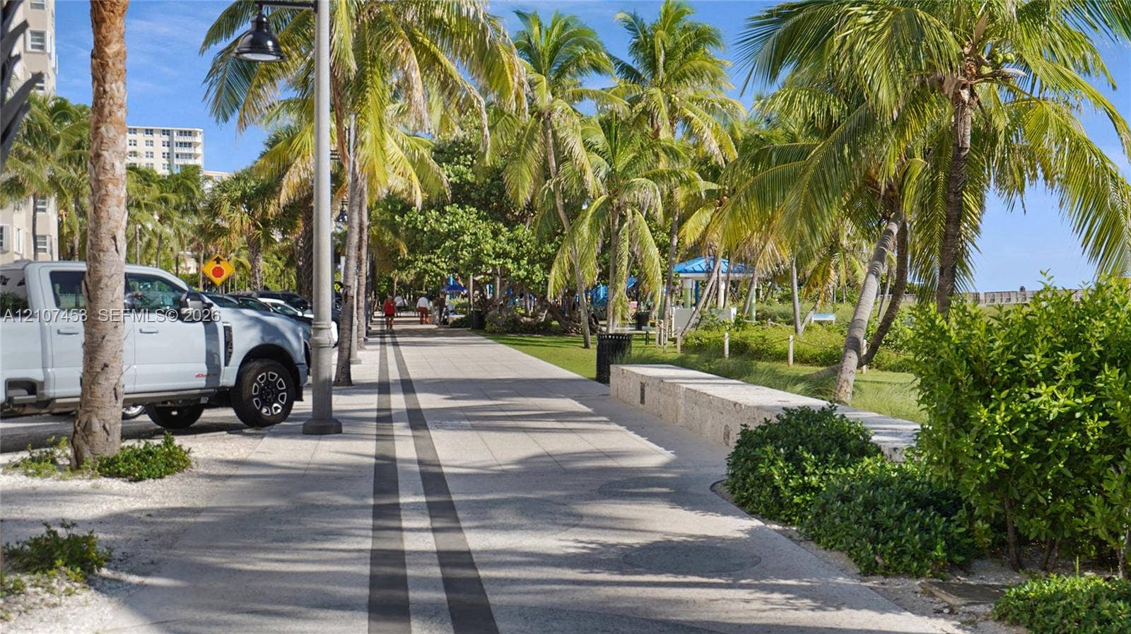 111 N Pompano Beach Boulevard, #304, Pompano Beach, FL 33062 Paved promenade featuring stone-finish hardscaping, mature palm trees, integrated stone seating, and modern post lighting
