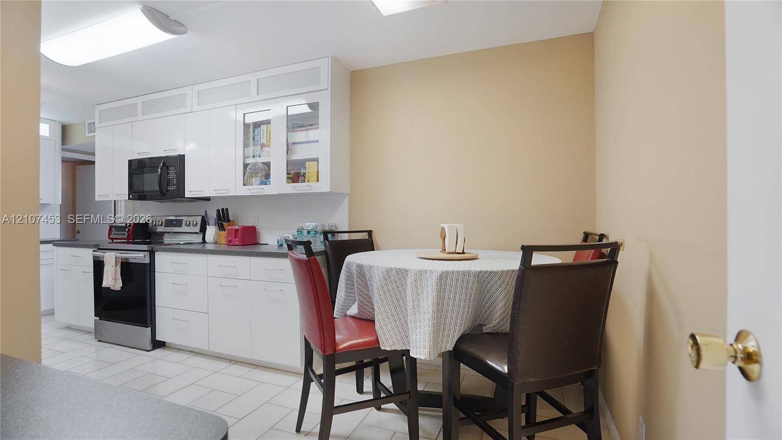 111 N Pompano Beach Boulevard, #304, Pompano Beach, FL 33062 Kitchen featuring high-gloss white cabinetry, glass-paneled upper cabinets, stainless steel appliances, and ceramic tile flooring