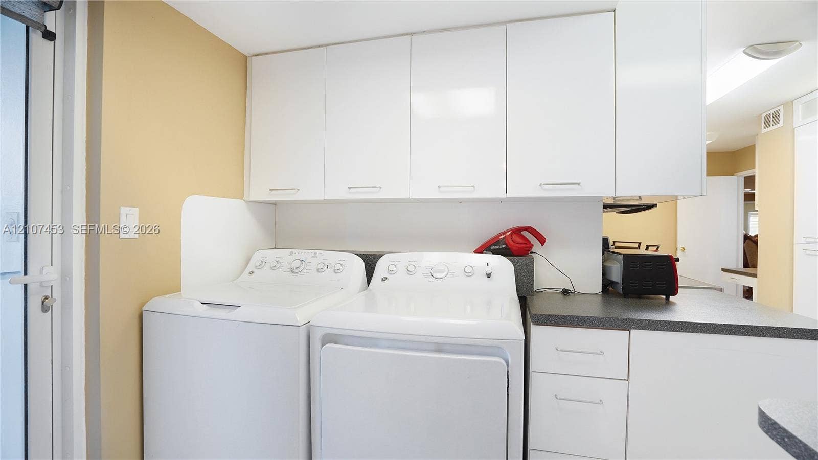 111 N Pompano Beach Boulevard, #304, Pompano Beach, FL 33062 Laundry area featuring white cabinetry, solid-surface countertops, and dedicated workspace