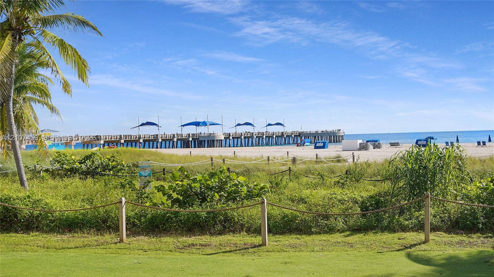 111 N Pompano Beach Boulevard, #304, Pompano Beach, FL 33062 Coastal property featuring manicured grass, a rope-lined perimeter, native sand dunes, and mature palm trees