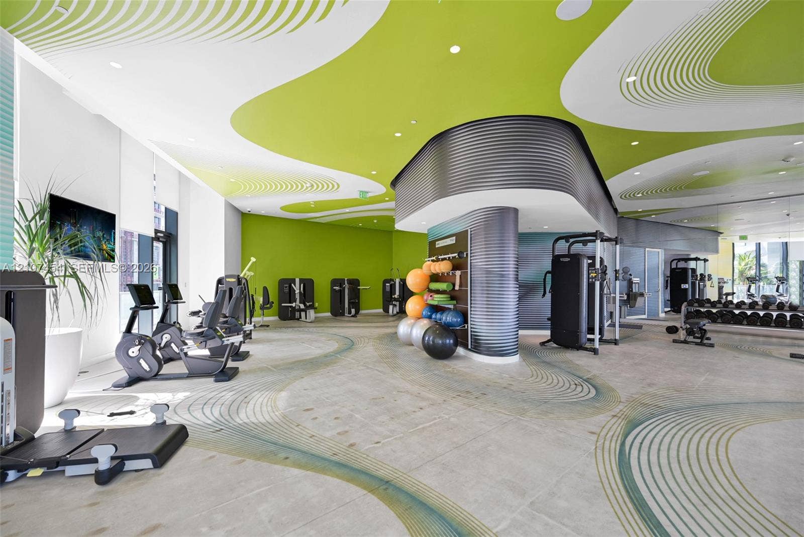 501 NE 31st Street, #1906, Miami, FL 33137 Fitness center featuring expansive floor-to-ceiling windows, high-contrast patterned ceiling, curved corrugated-metal structural accents, and large-format tile flooring