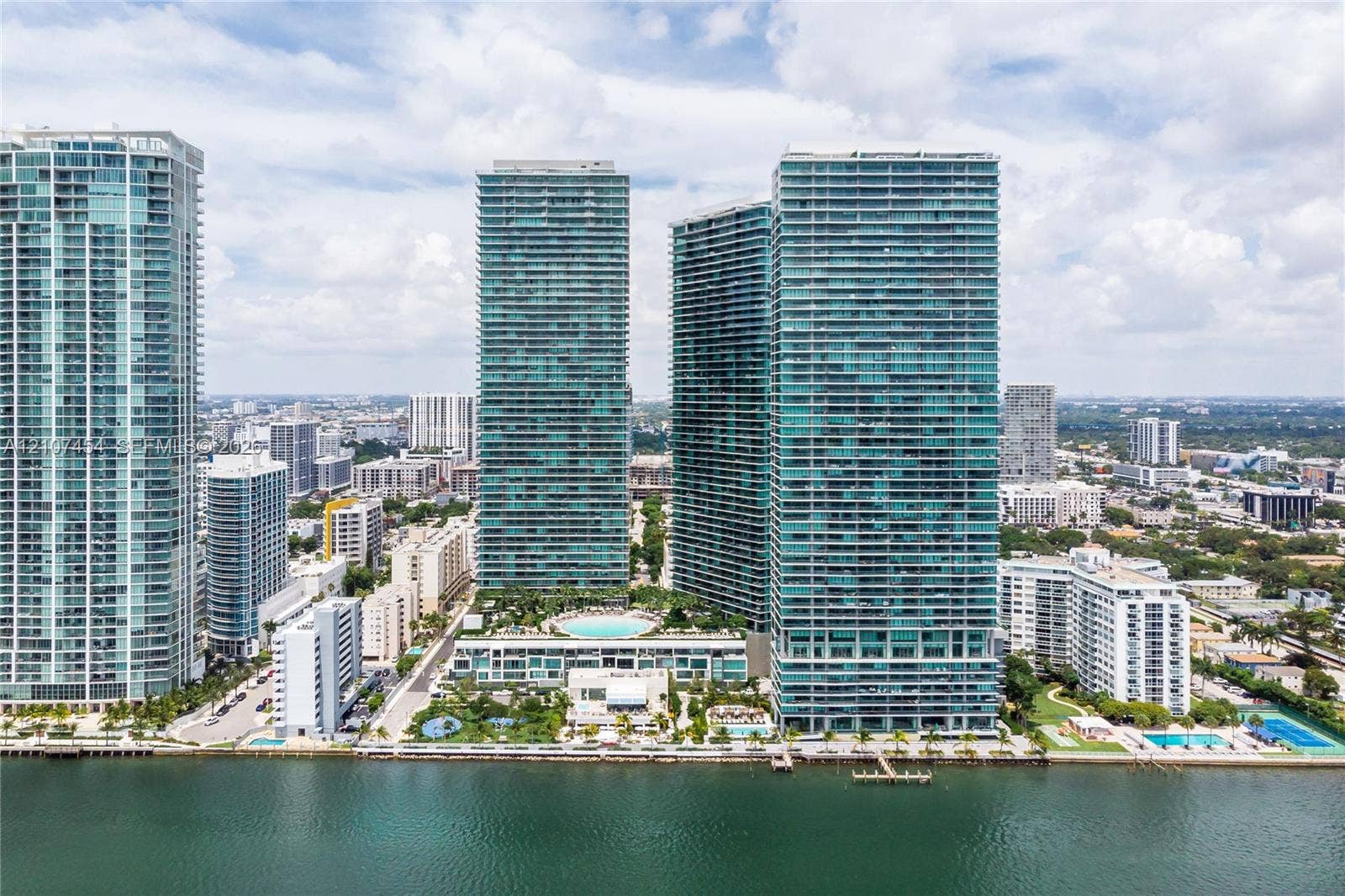 501 NE 31st Street, #1906, Miami, FL 33137 High-rise complex featuring glass-facade towers, an elevated outdoor pool, landscaped podium deck, and direct waterfront placement
