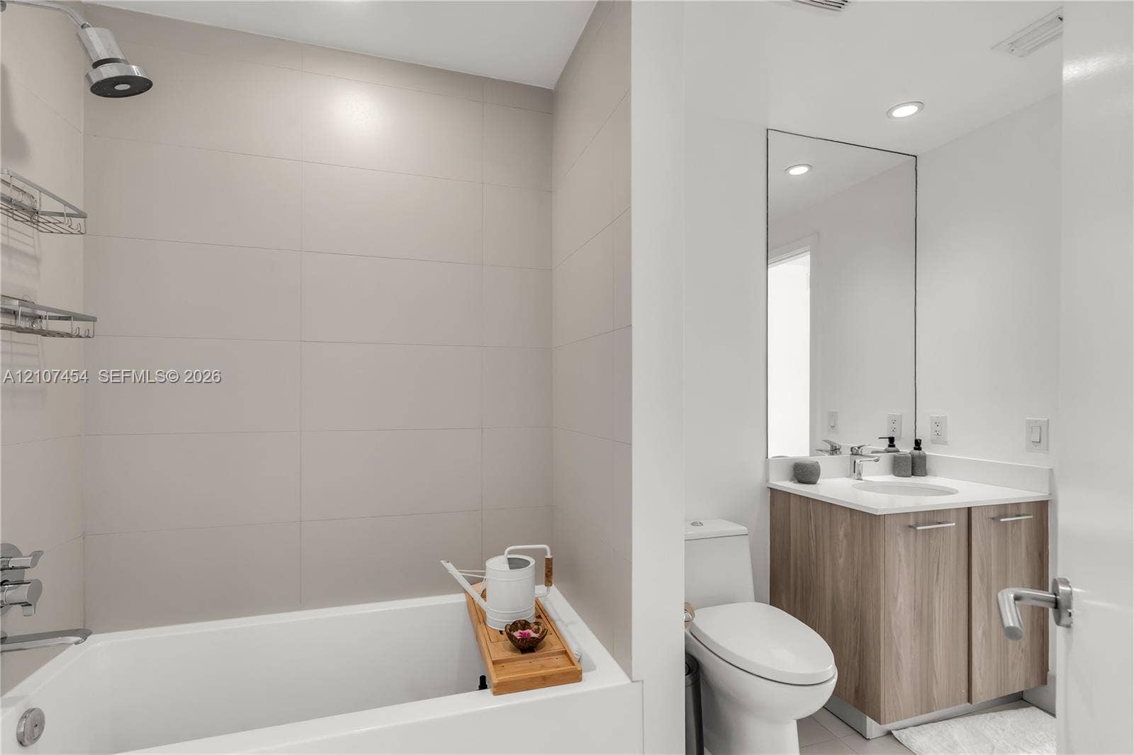 501 NE 31st Street, #1906, Miami, FL 33137 Bathroom featuring large-format wall tile, wood-finish cabinetry, a rectangular undermount sink, a tall frameless mirror, and recessed lighting