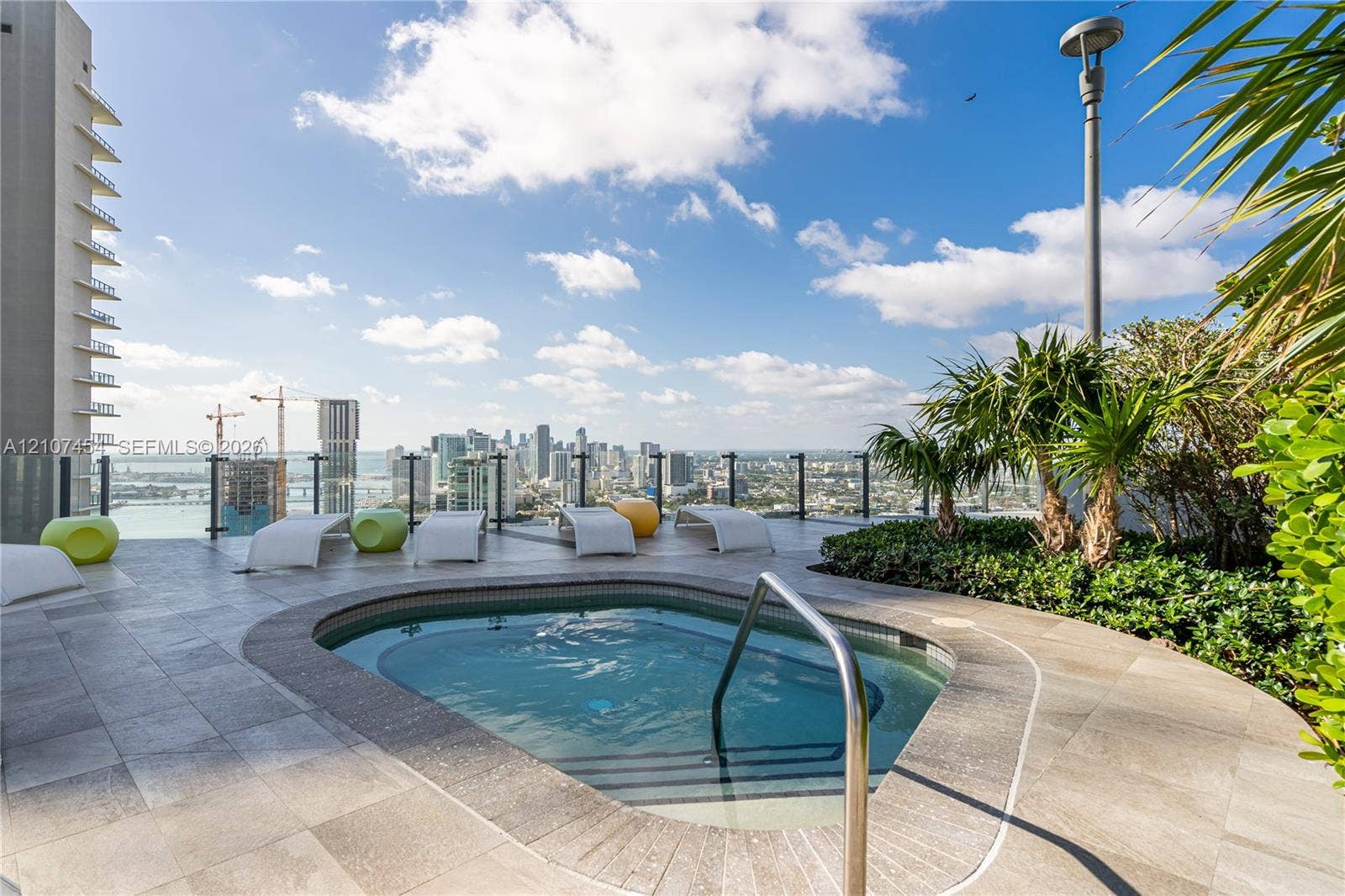 501 NE 31st Street, #1906, Miami, FL 33137 Rooftop terrace featuring a built-in spa, stone-tile decking, glass panel railing, and integrated landscaping
