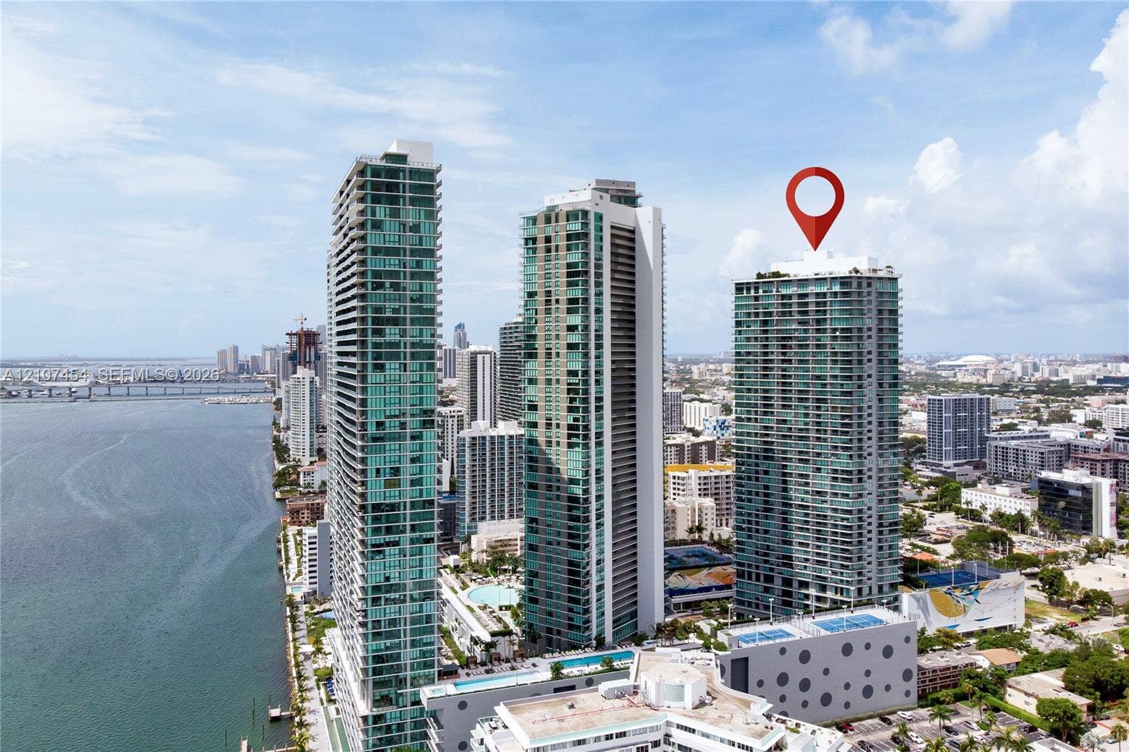 501 NE 31st Street, #1906, Miami, FL 33137 High-rise glass facade condominium tower featuring private balconies, integrated parking structure, and rooftop amenity deck, situated within a coastal urban environment