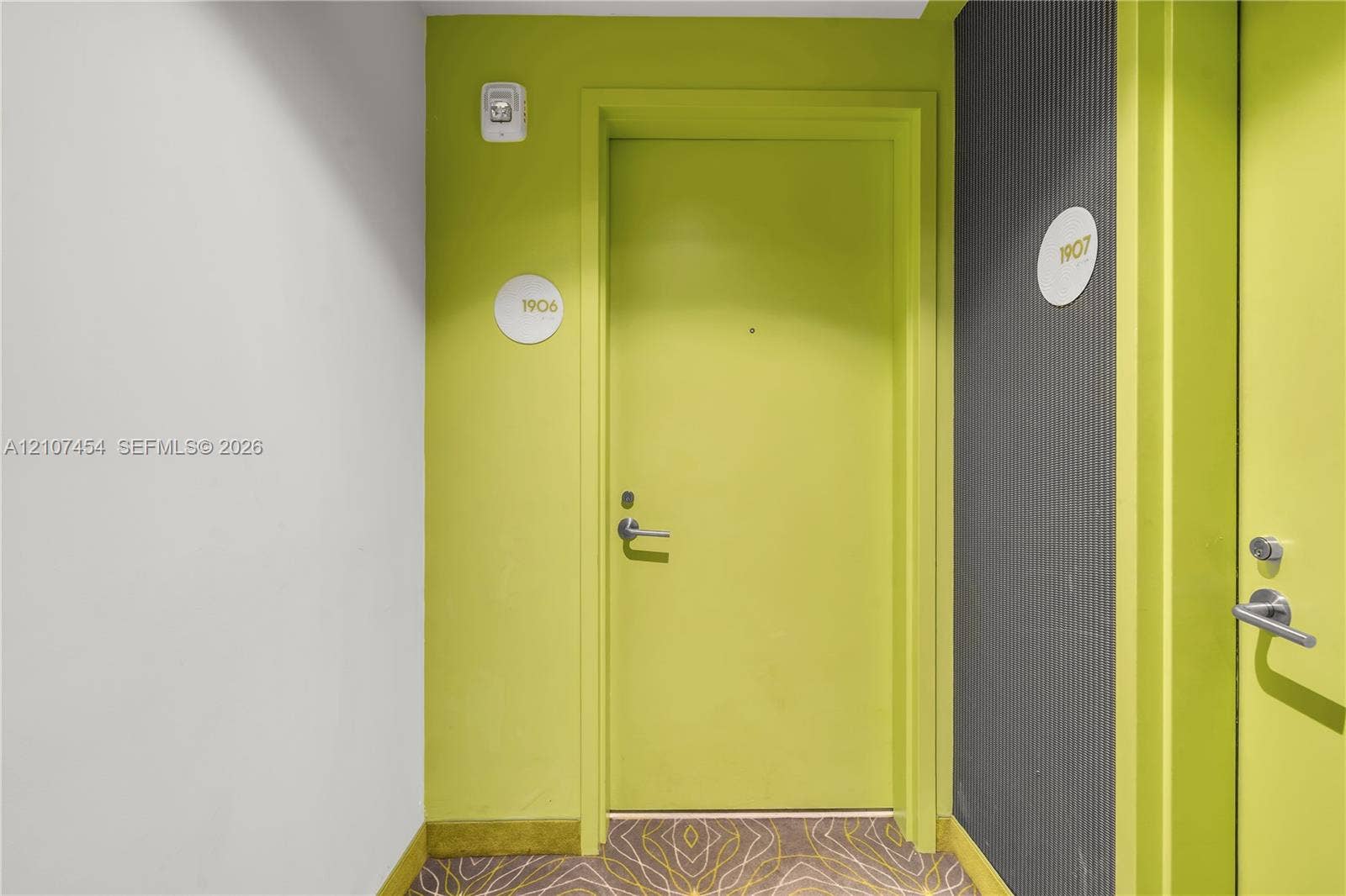 501 NE 31st Street, #1906, Miami, FL 33137 Entryway featuring lime green doors with brushed metal hardware, circular unit signage, and textured dark grey wall paneling