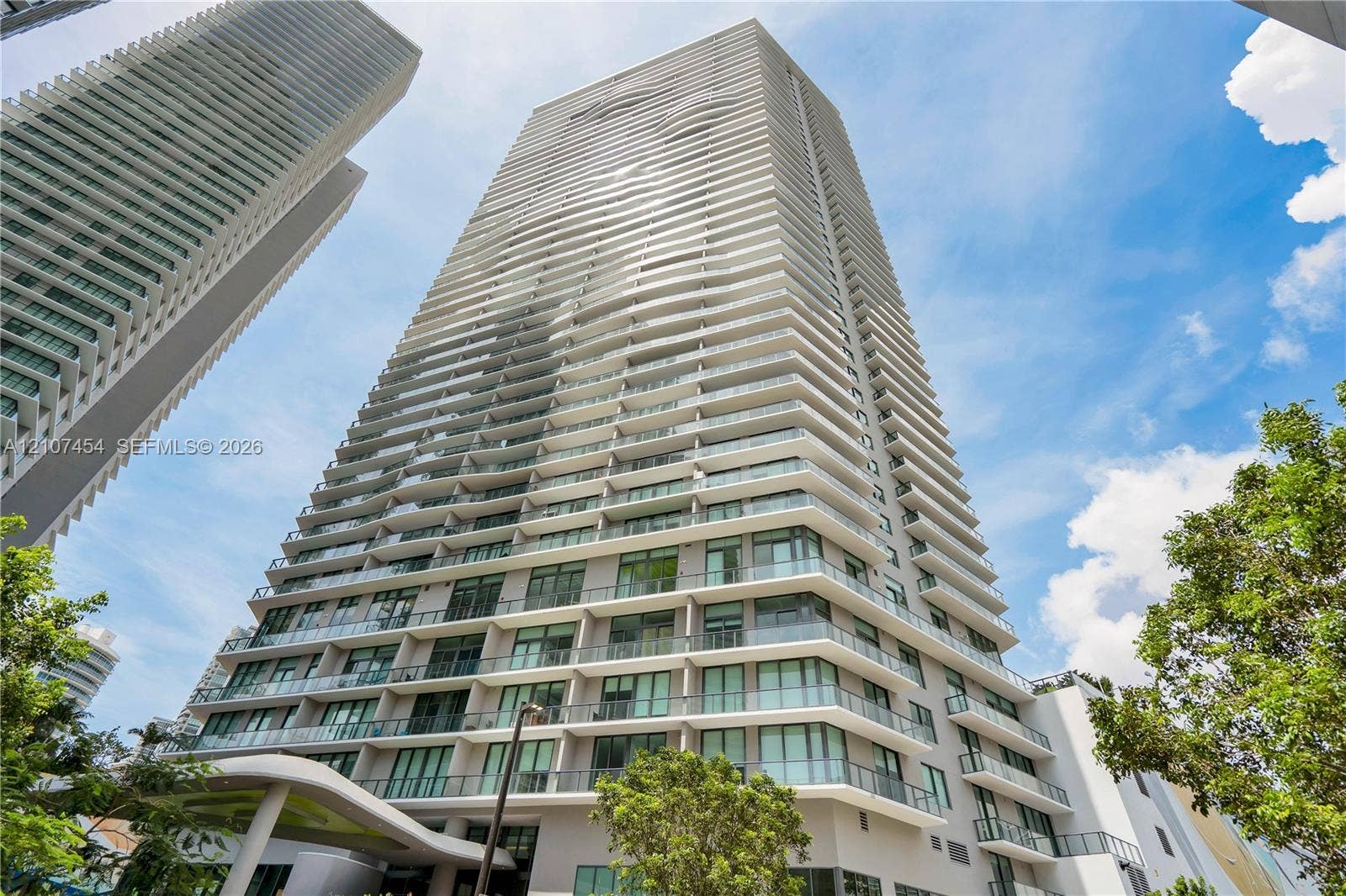 501 NE 31st Street, #1906, Miami, FL 33137 High-rise tower exterior featuring a multi-story facade, cantilevered balconies with glass railings, large-pane windows, and a structured concrete architectural design