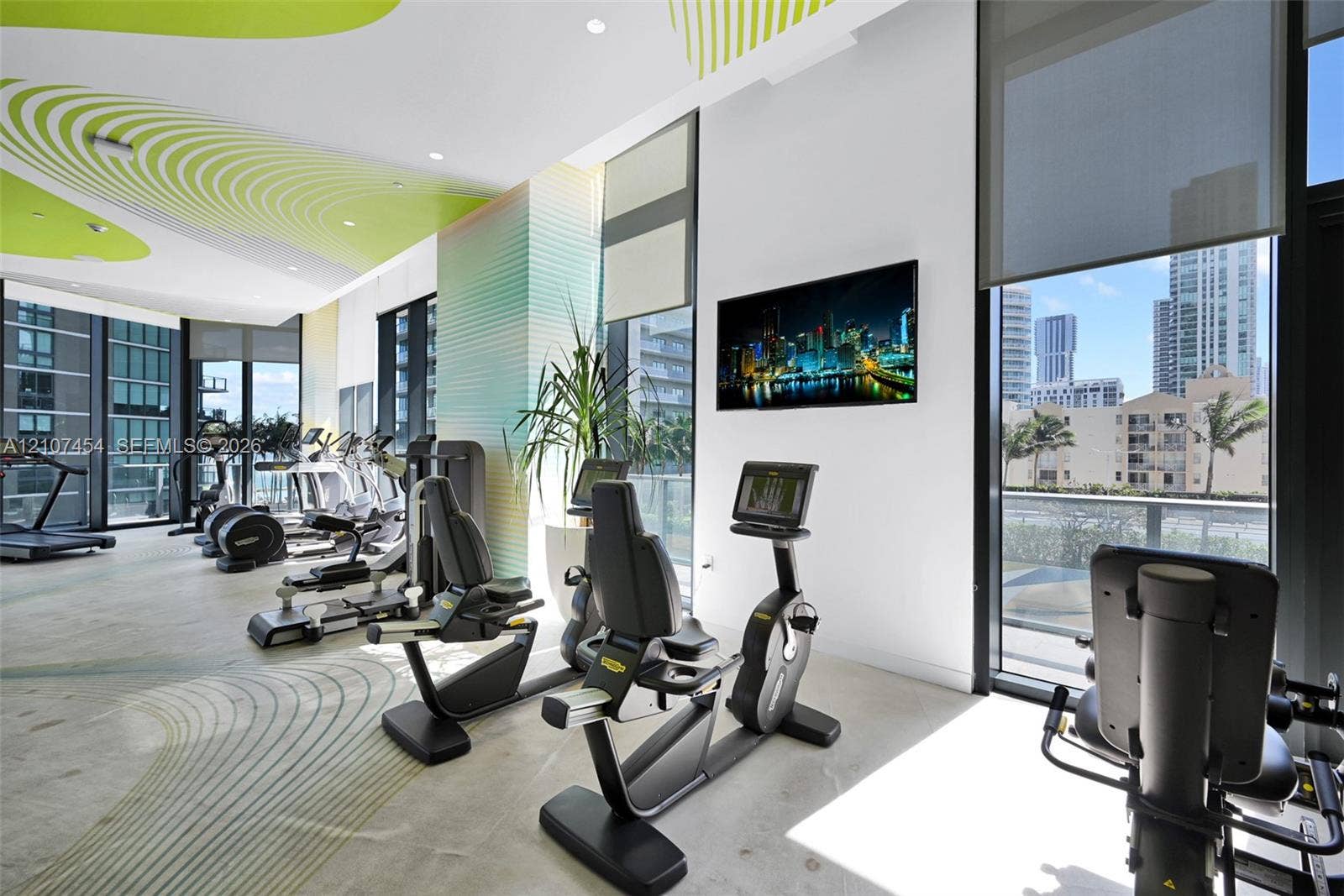 501 NE 31st Street, #1906, Miami, FL 33137 Fitness center featuring floor-to-ceiling windows, polished concrete flooring, custom graphic ceiling detail, and integrated solar shades