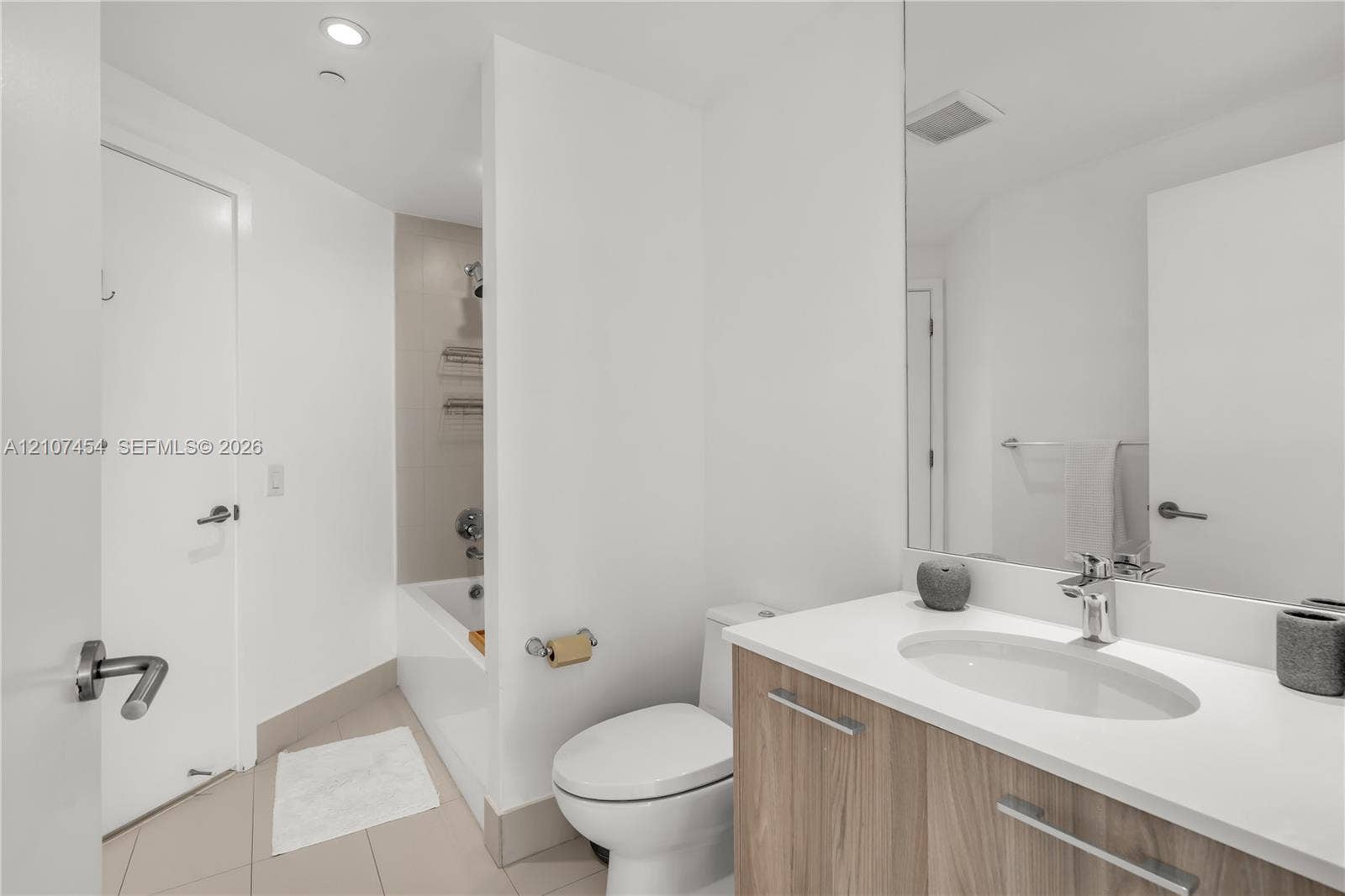 501 NE 31st Street, #1906, Miami, FL 33137 Vanity featuring a light wood-finish cabinet, white countertop with an integrated oval sink, and a full-width mirror