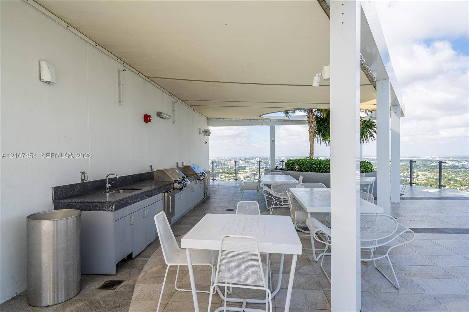 501 NE 31st Street, #1906, Miami, FL 33137 Covered outdoor terrace featuring a built-in kitchen, dark stone countertop, integrated stainless steel appliances, and metal railing