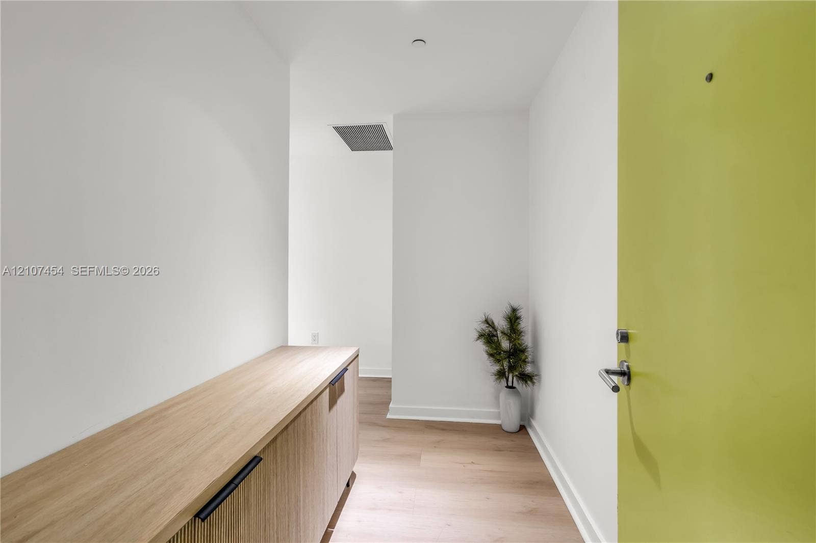 501 NE 31st Street, #1906, Miami, FL 33137 Entryway featuring a light-tone door with a modern lever handle, built-in wooden cabinetry with matte black hardware, and light wood-finish flooring