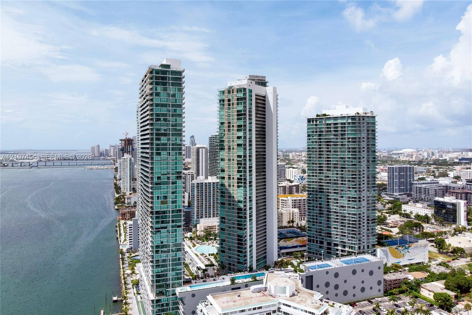 501 NE 31st Street, #1906, Miami, FL 33137 High-rise towers featuring glass facades, multi-level podium structures, swimming pools, and concrete parking facilities, situated on the waterfront