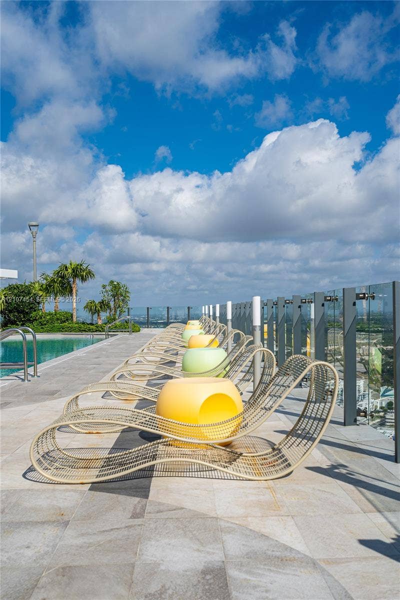 501 NE 31st Street, #1906, Miami, FL 33137 Rooftop swimming pool area featuring stone tile decking and a glass panel railing