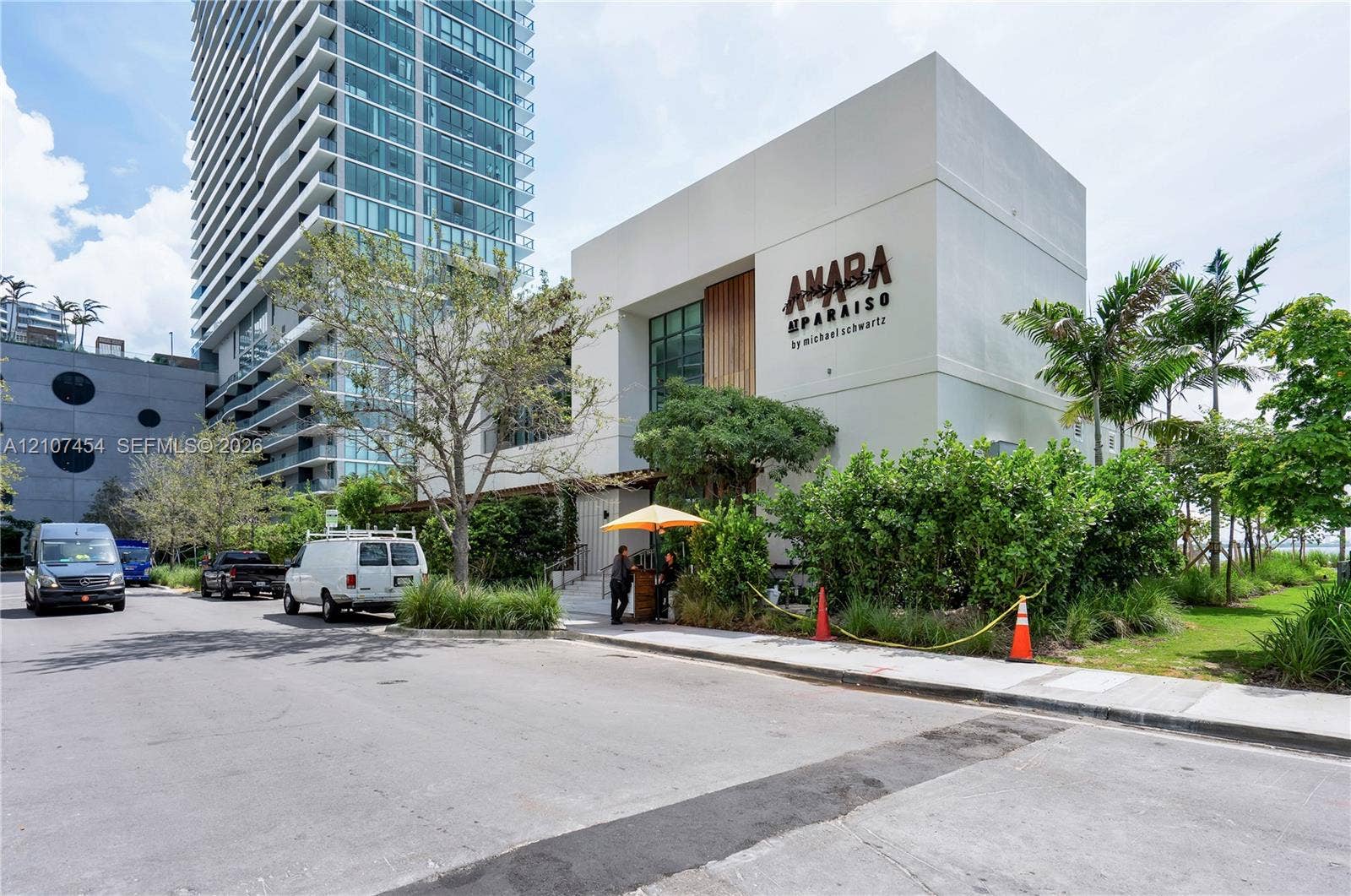 501 NE 31st Street, #1906, Miami, FL 33137 Modern low-rise structure featuring a concrete exterior, wood-paneled accent wall, expansive glass windows, and surrounding manicured landscape