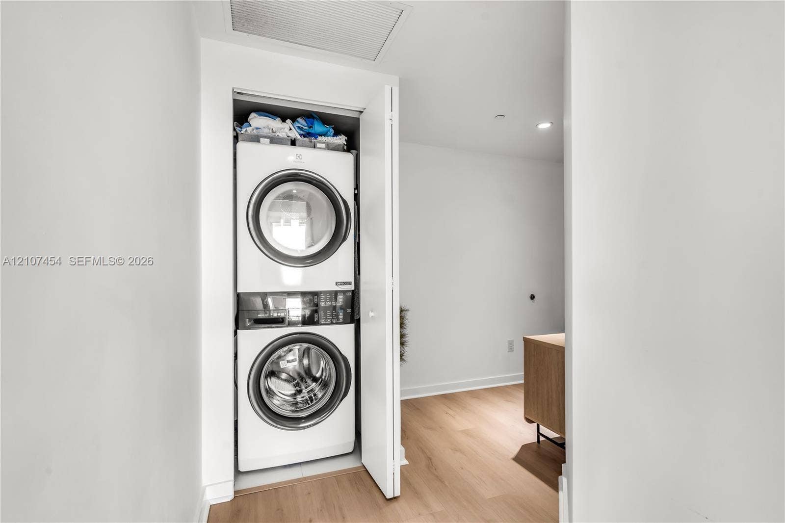 501 NE 31st Street, #1906, Miami, FL 33137 Stacked front-loading washer and dryer unit enclosed in a dedicated closet featuring light wood-finish flooring