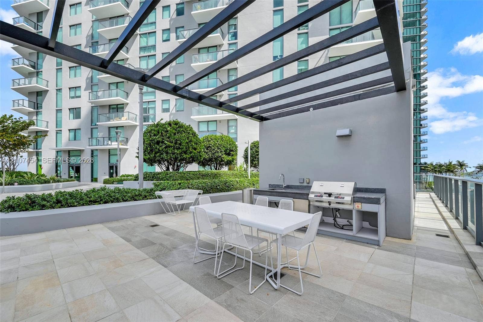 501 NE 31st Street, #1906, Miami, FL 33137 Outdoor patio featuring stone-tile flooring, a metal pergola, and a built-in kitchen station with a sink and grill
