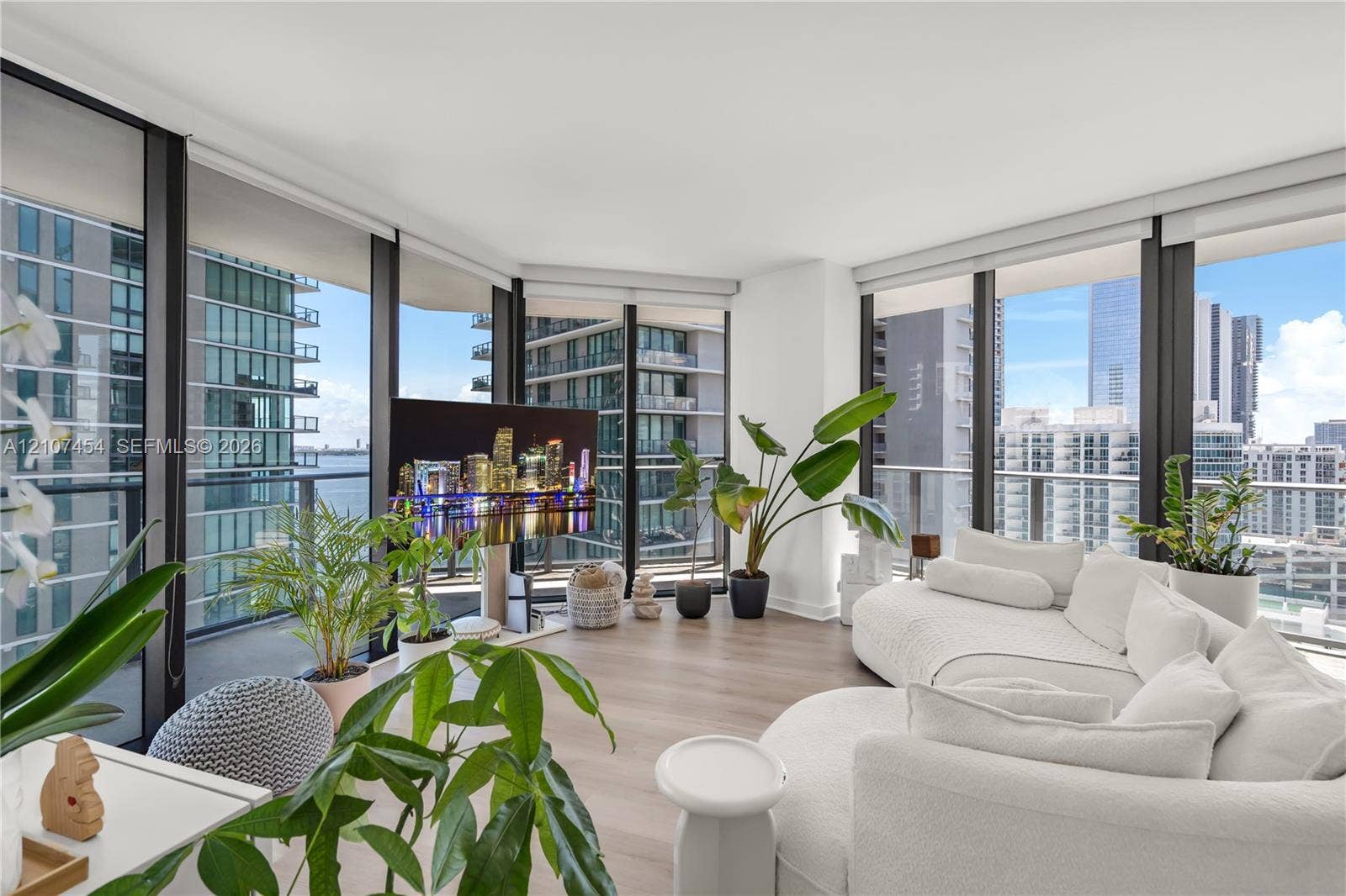 501 NE 31st Street, #1906, Miami, FL 33137 Floor-to-ceiling glass walls, wrap-around balcony with metal railing, and neutral-toned wood-finish flooring