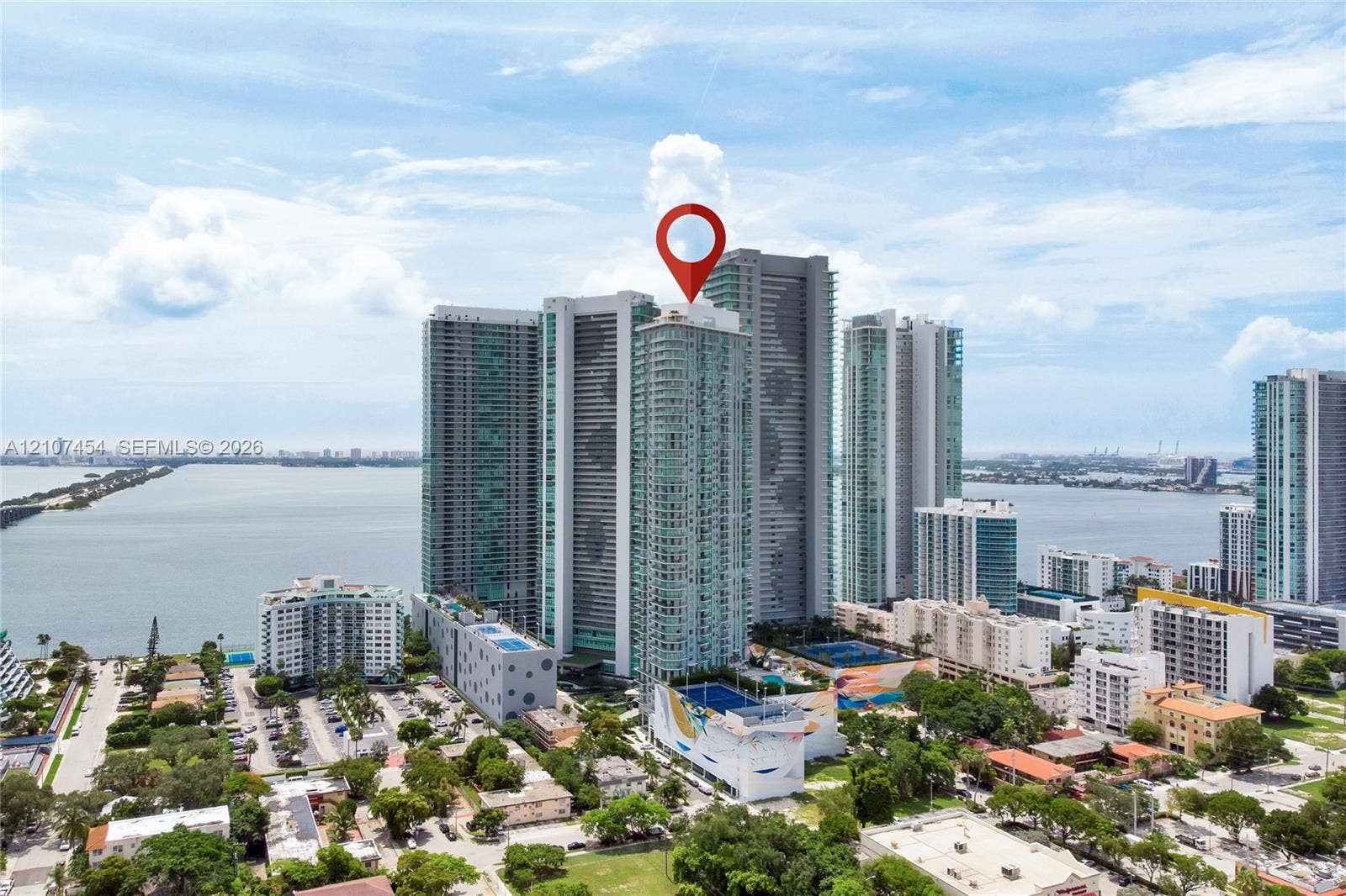 501 NE 31st Street, #1906, Miami, FL 33137 High-rise residential tower featuring a glass facade, expansive water proximity, and a multi-level structure with prominent podium parking and podium-level recreational amenities