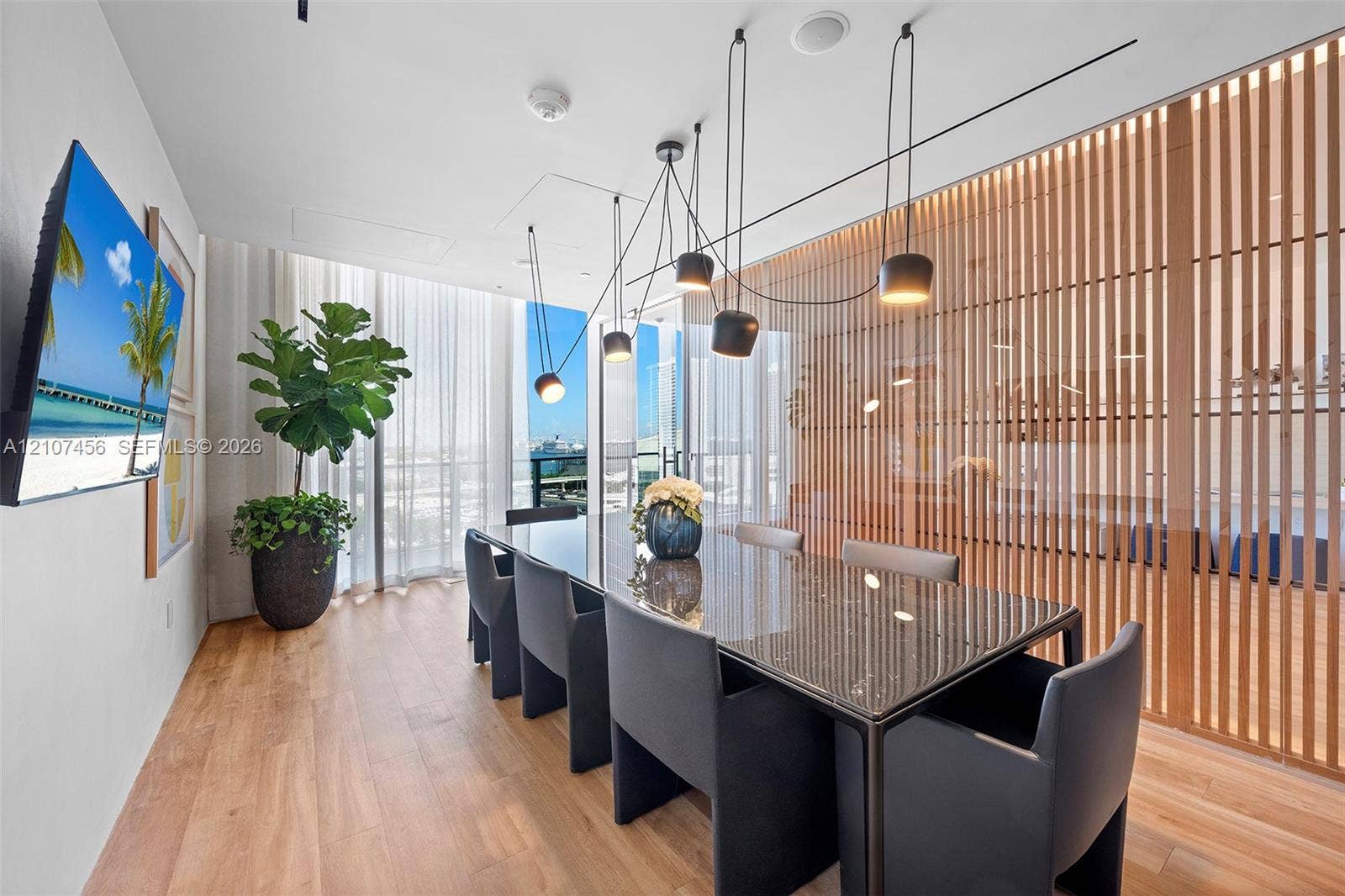 1400 Biscayne Boulevard, #2604, Miami, Miami, FL 33132 Floor-to-ceiling windows, wood-finish flooring, decorative vertical slat room divider, and multi-pendant architectural lighting