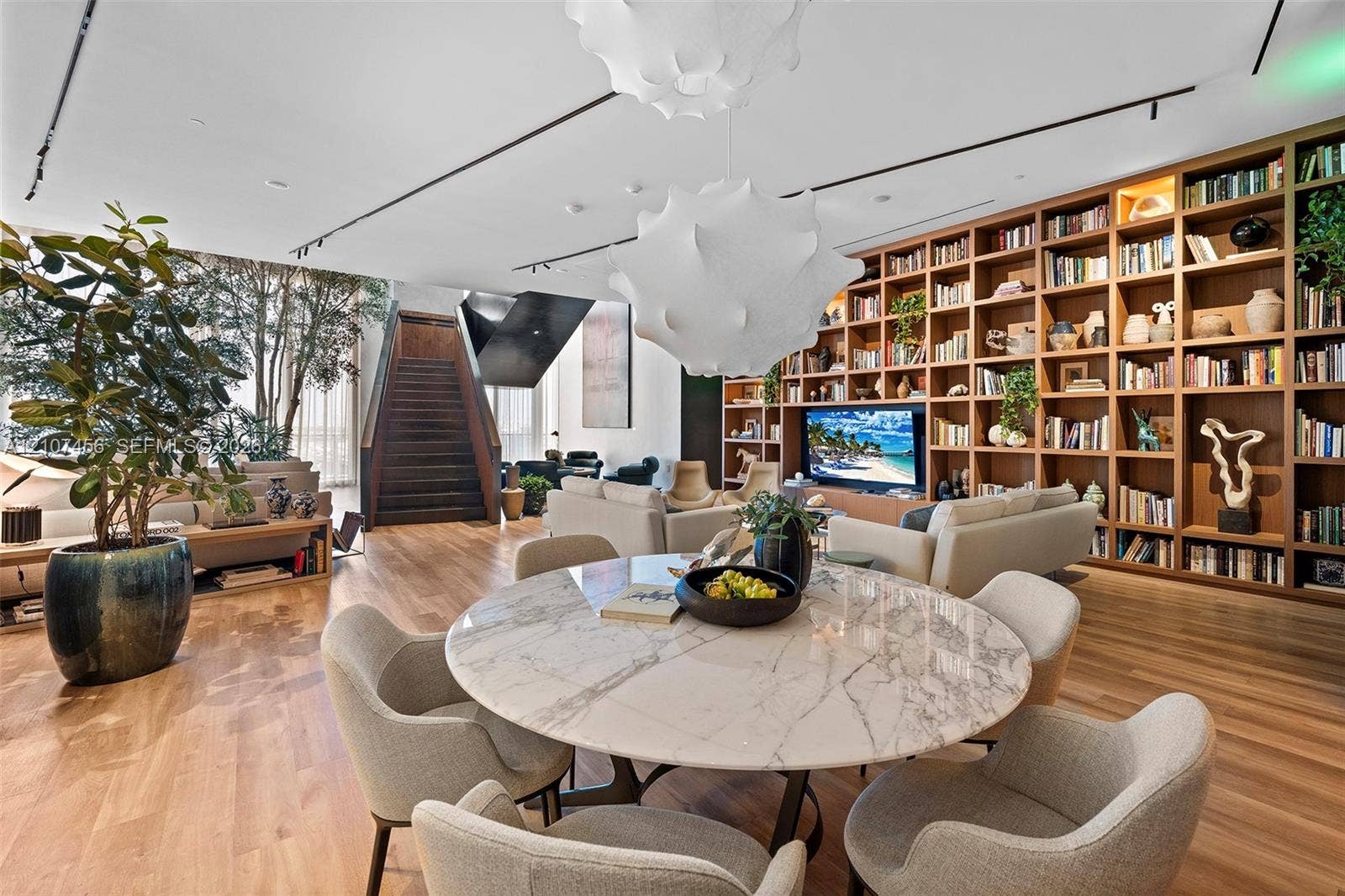 1400 Biscayne Boulevard, #2604, Miami, Miami, FL 33132 Open-concept living space featuring floor-to-ceiling built-in wooden shelving, track lighting, sculptural pendant lighting, wood-finish flooring, and a bespoke staircase