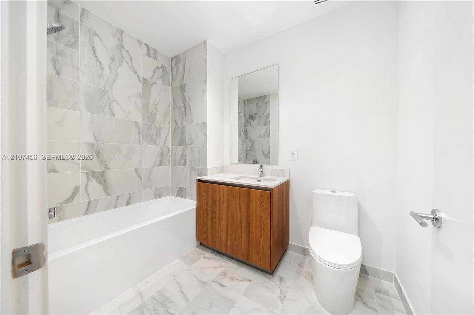 1400 Biscayne Boulevard, #2604, Miami, Miami, FL 33132 Bathroom featuring wood-finish vanity cabinetry, integrated sink with chrome faucet, wall-mounted mirror, soaking tub with tile surround, and tile flooring